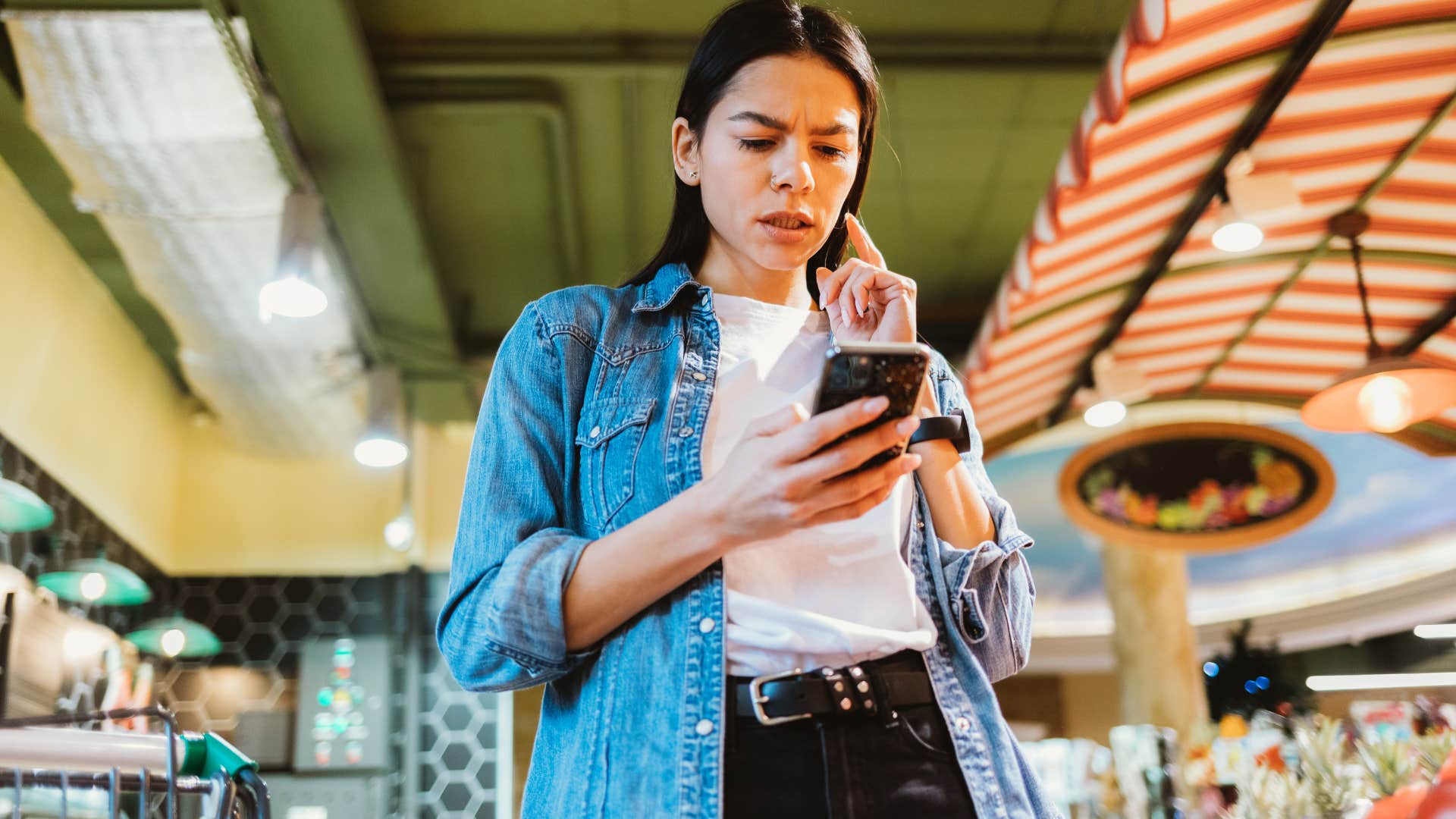 woman looking at her phone at the grocery store