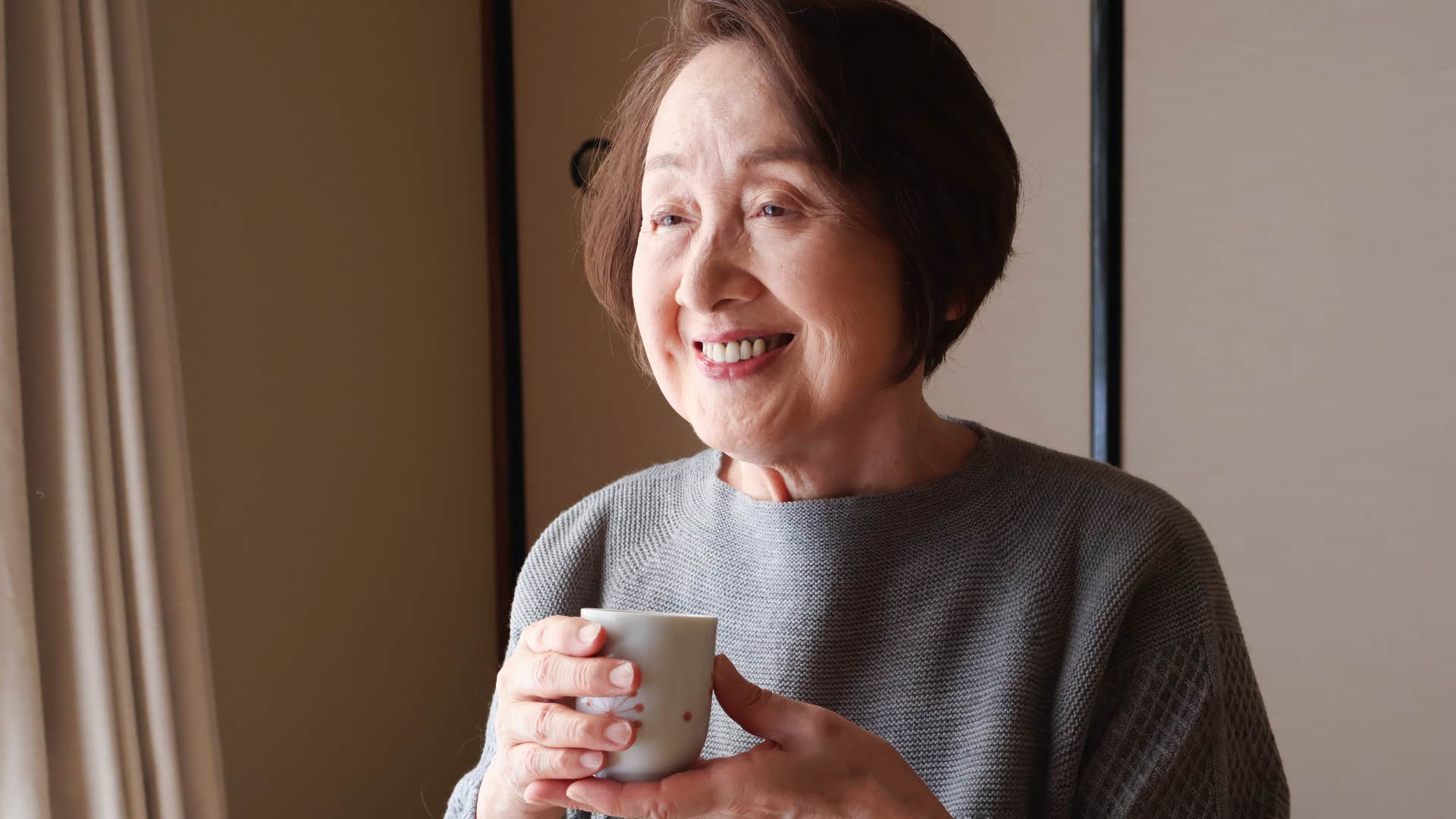 intuitive people who prefer tea over coffee usually have these surprisingly grounded personality traits Intuitive woman smiling with tea.