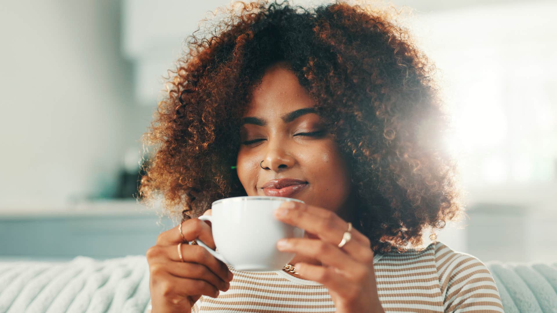 self-aware people who prefer tea over coffee usually have these surprisingly grounded personality traits Self-aware woman smiling and drinking tea.