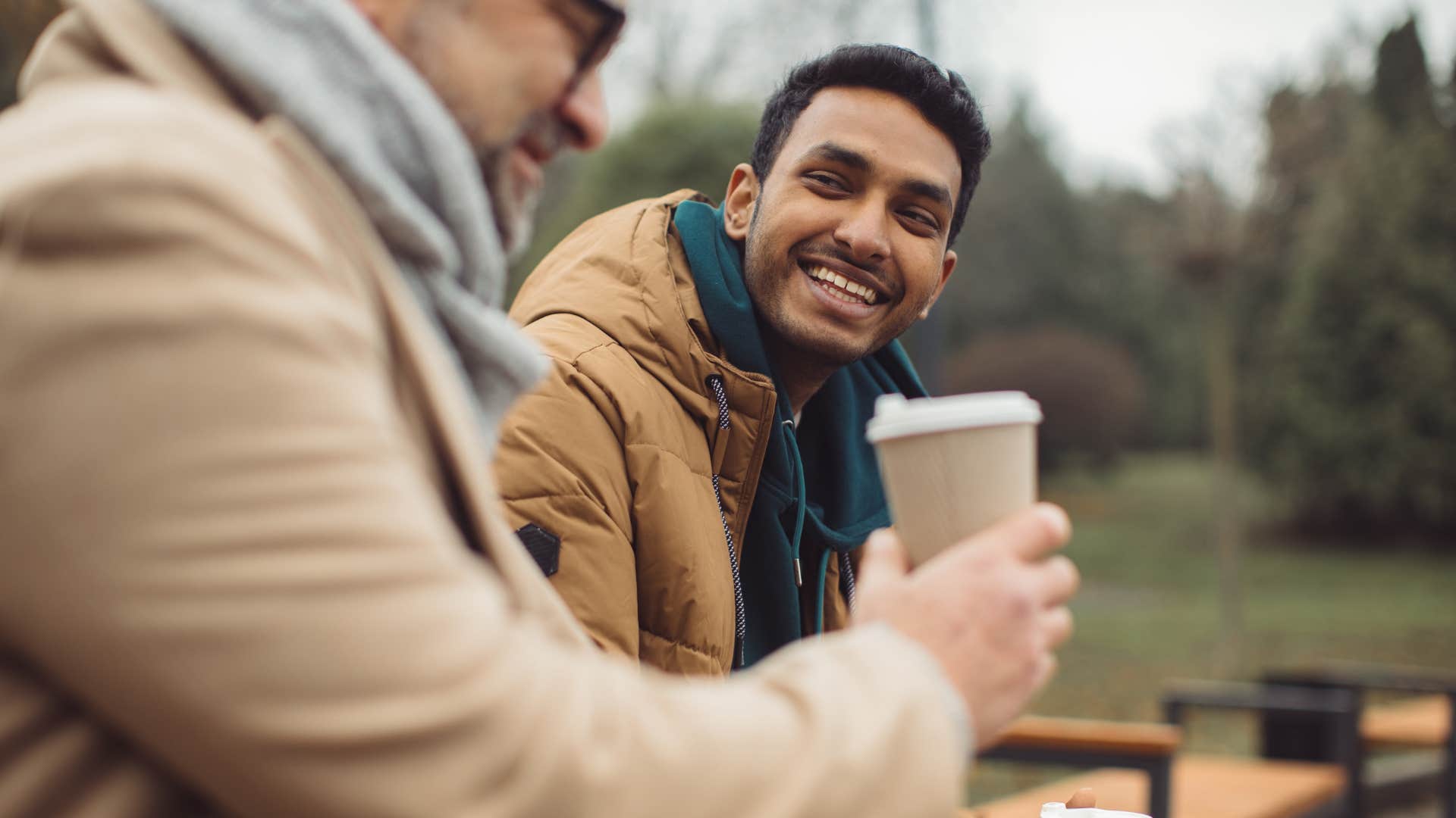 young men smiling on park bench