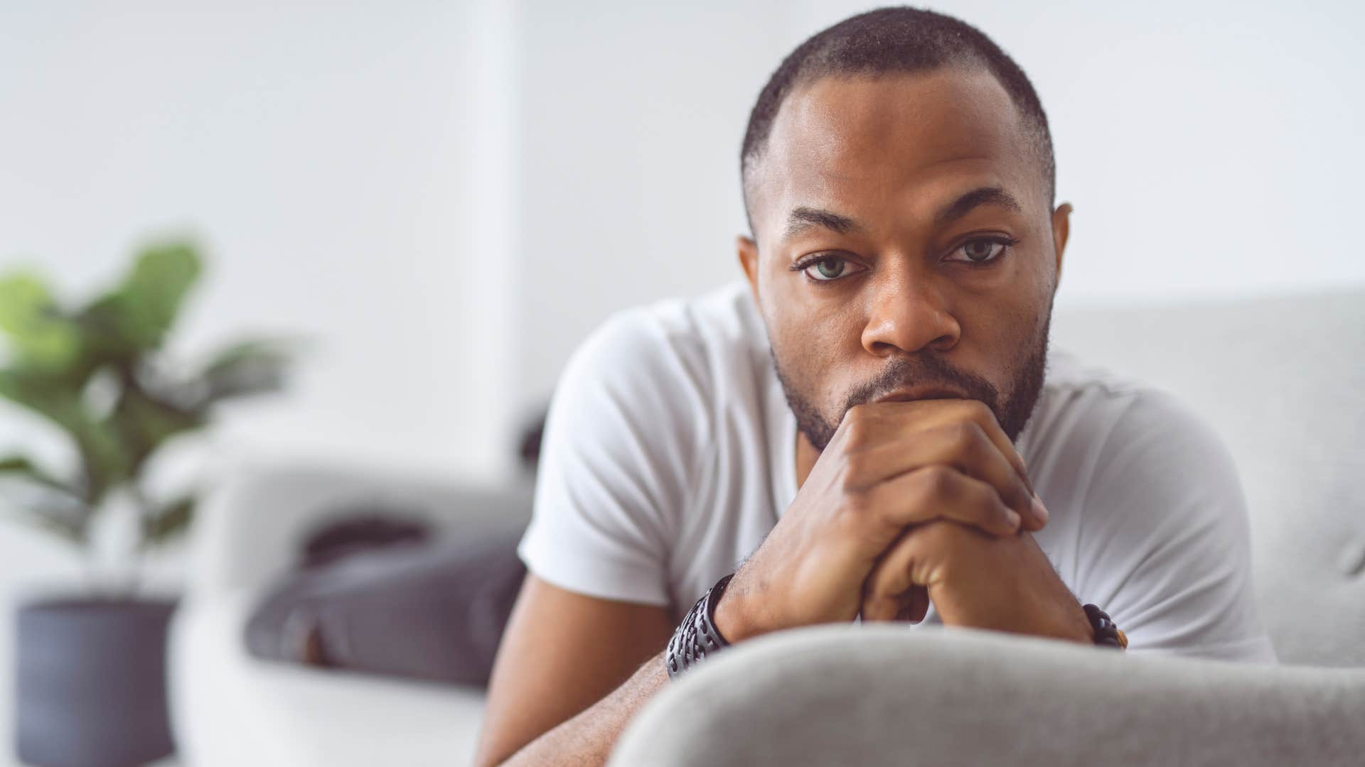 man who fears being a burden sitting on his couch alone