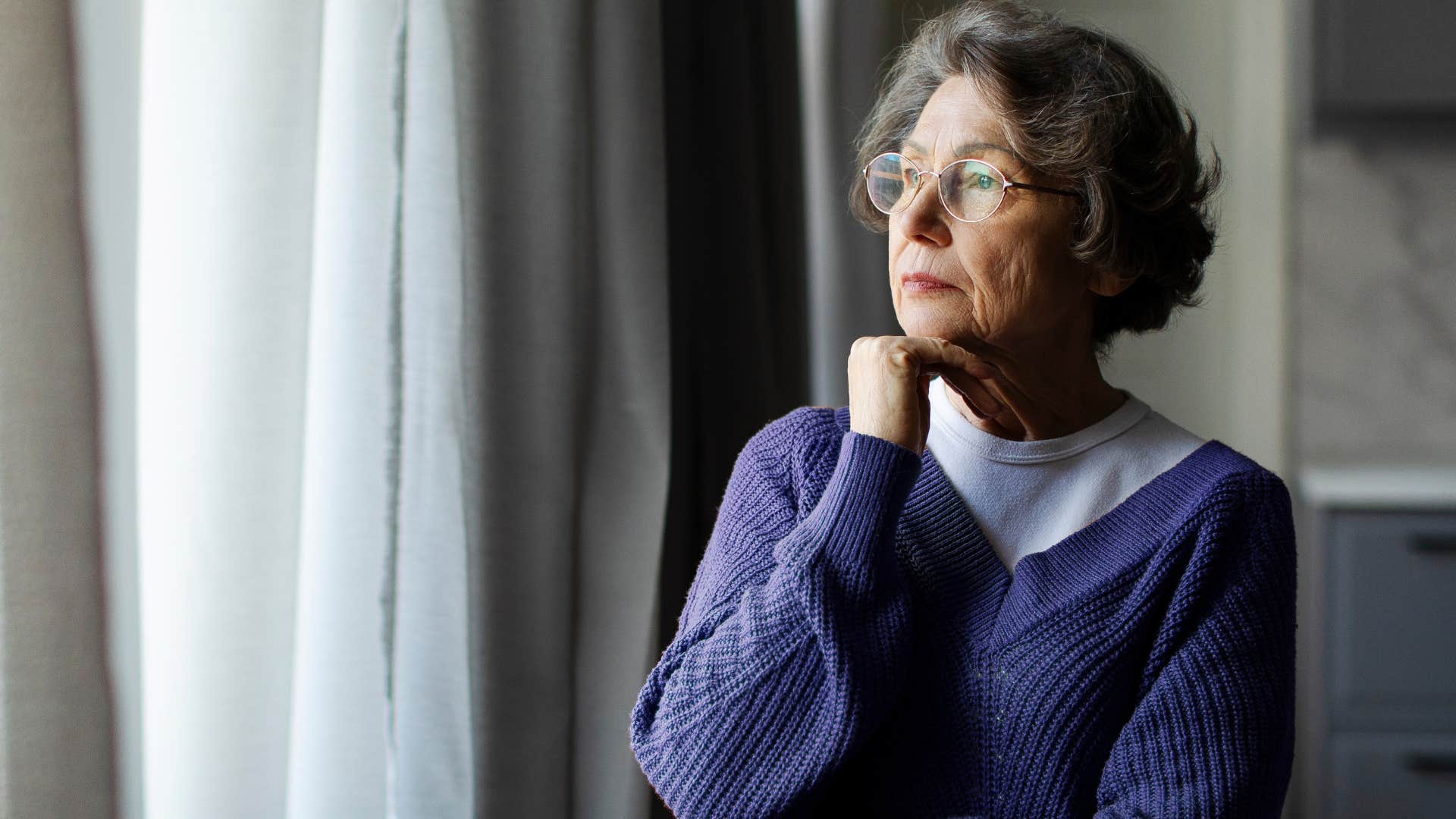 woman who's outgrown their social circle looking out a window alone