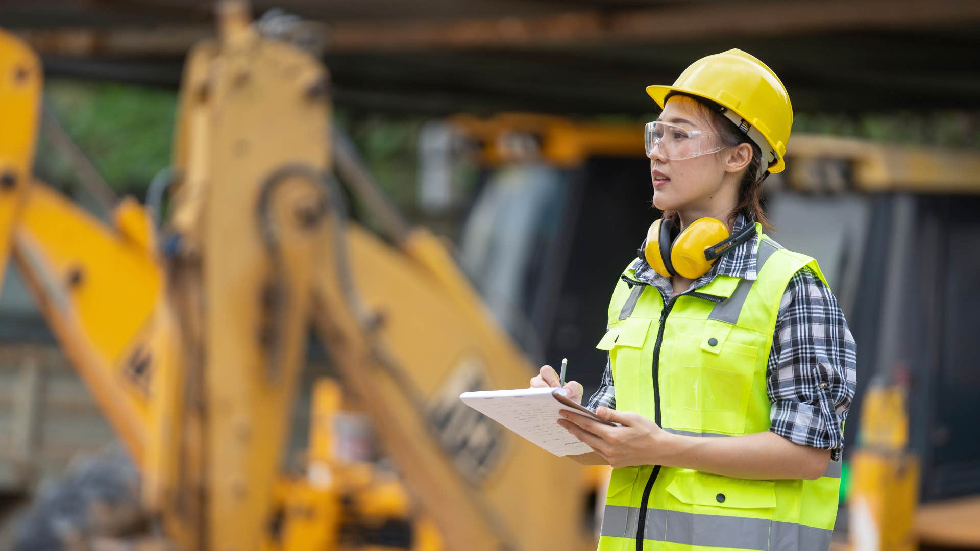 construction worker holding a clipboard in front of truck