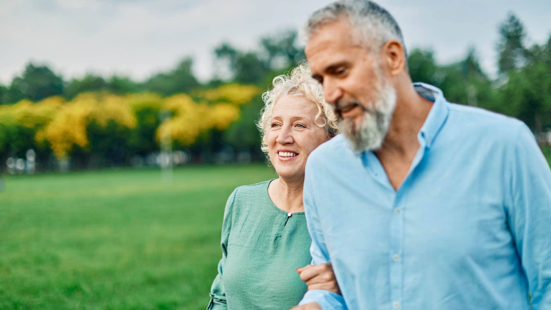 Couple who gives each other grace smiling outside.