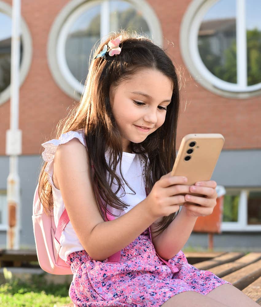 young girl using smartphone at school