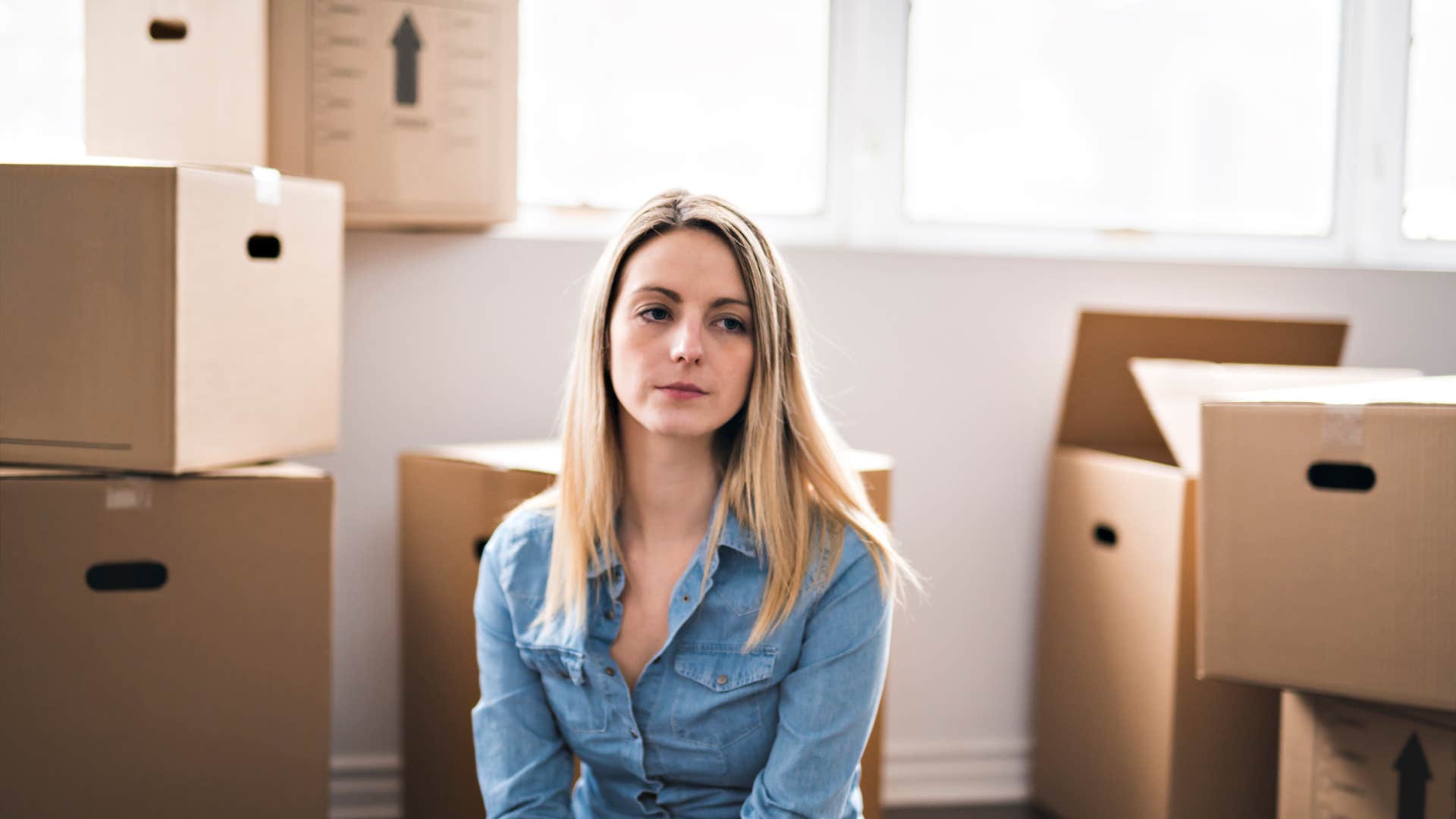 woman sitting in unfurnished room with unloaded boxes