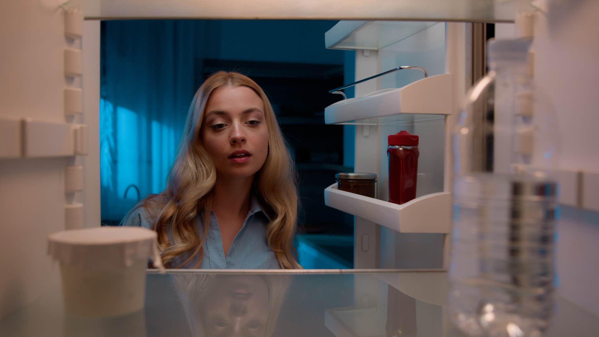 woman looking in empty fridge