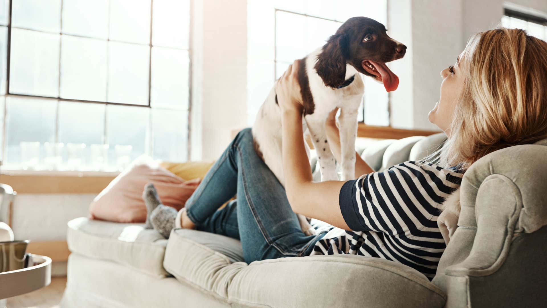 woman playing with dog on couch