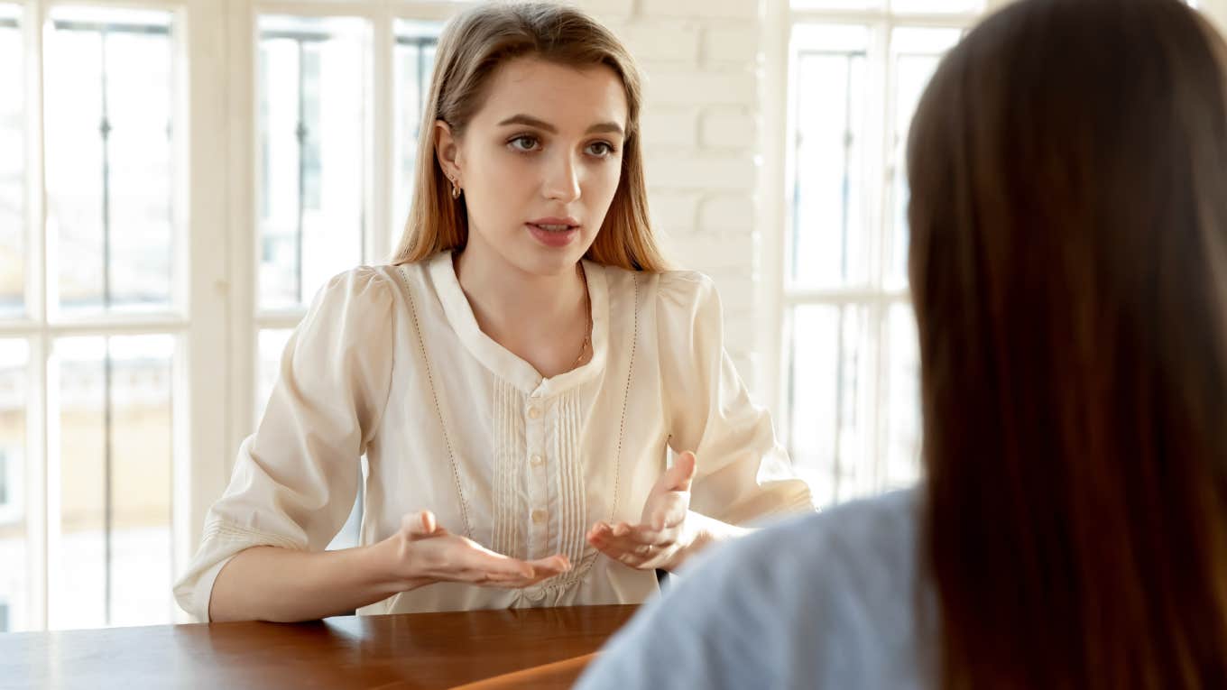 woman having conversation with friend sitting across from her