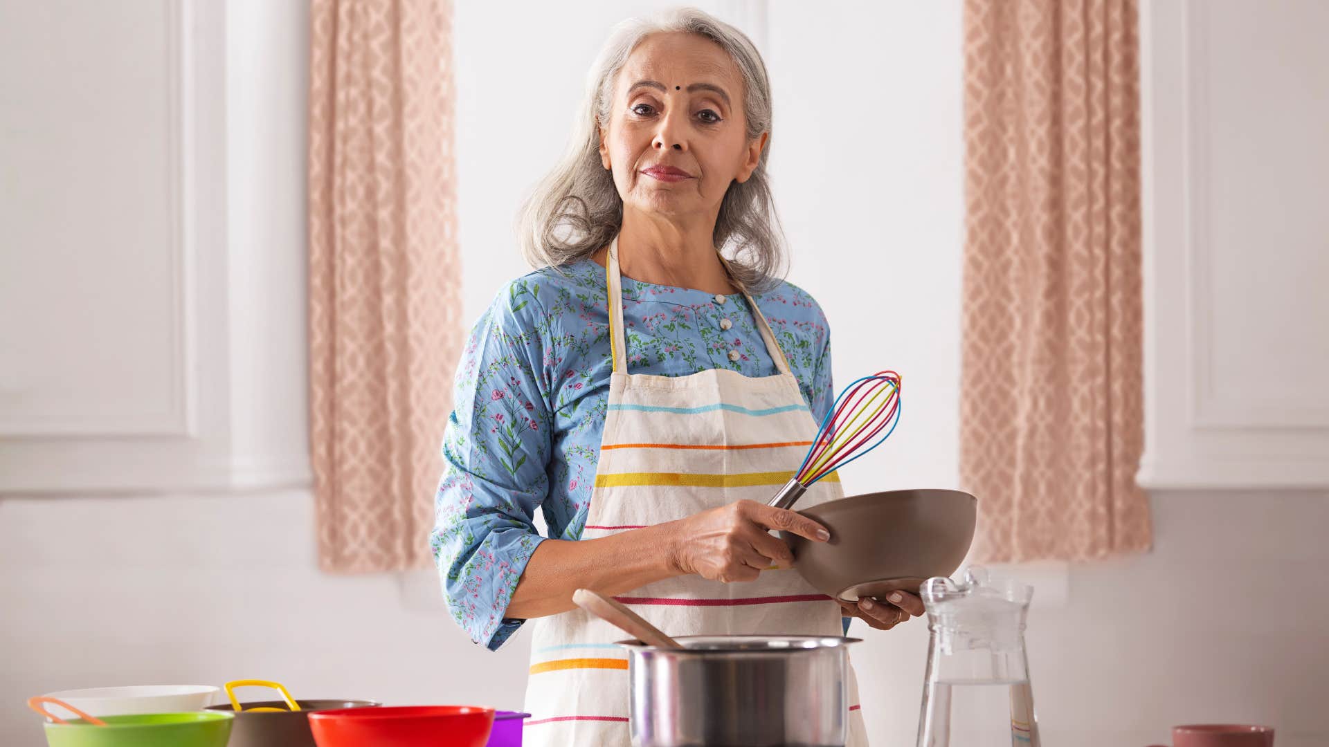 woman in blue shirt refuses to use old kitchen gadget that are collecting dust and stirs with whisk instead