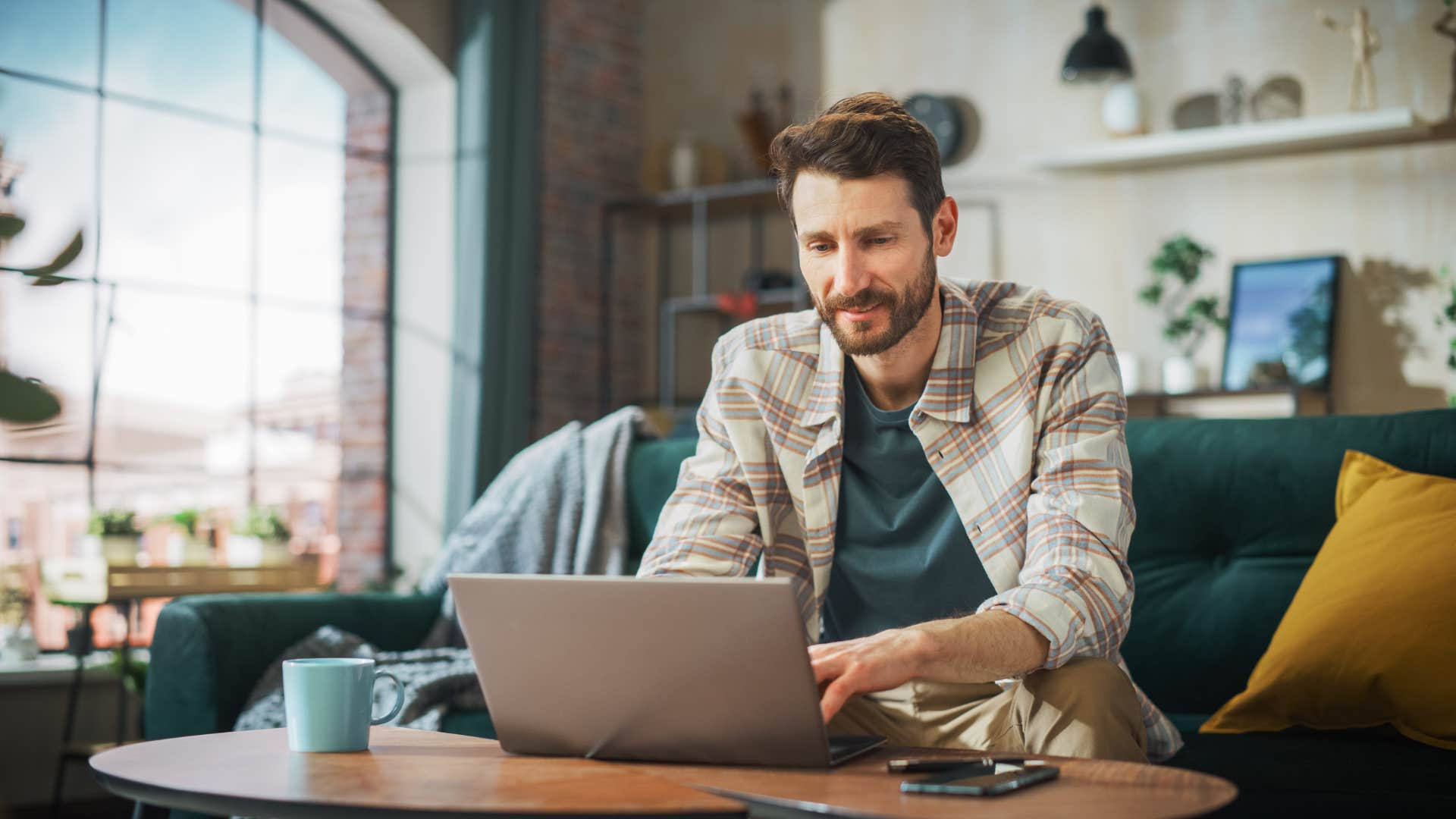 man in green shirt using outdated tech as he types for work