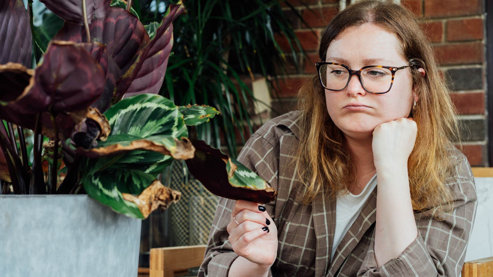 woman looking at dead plants in her home