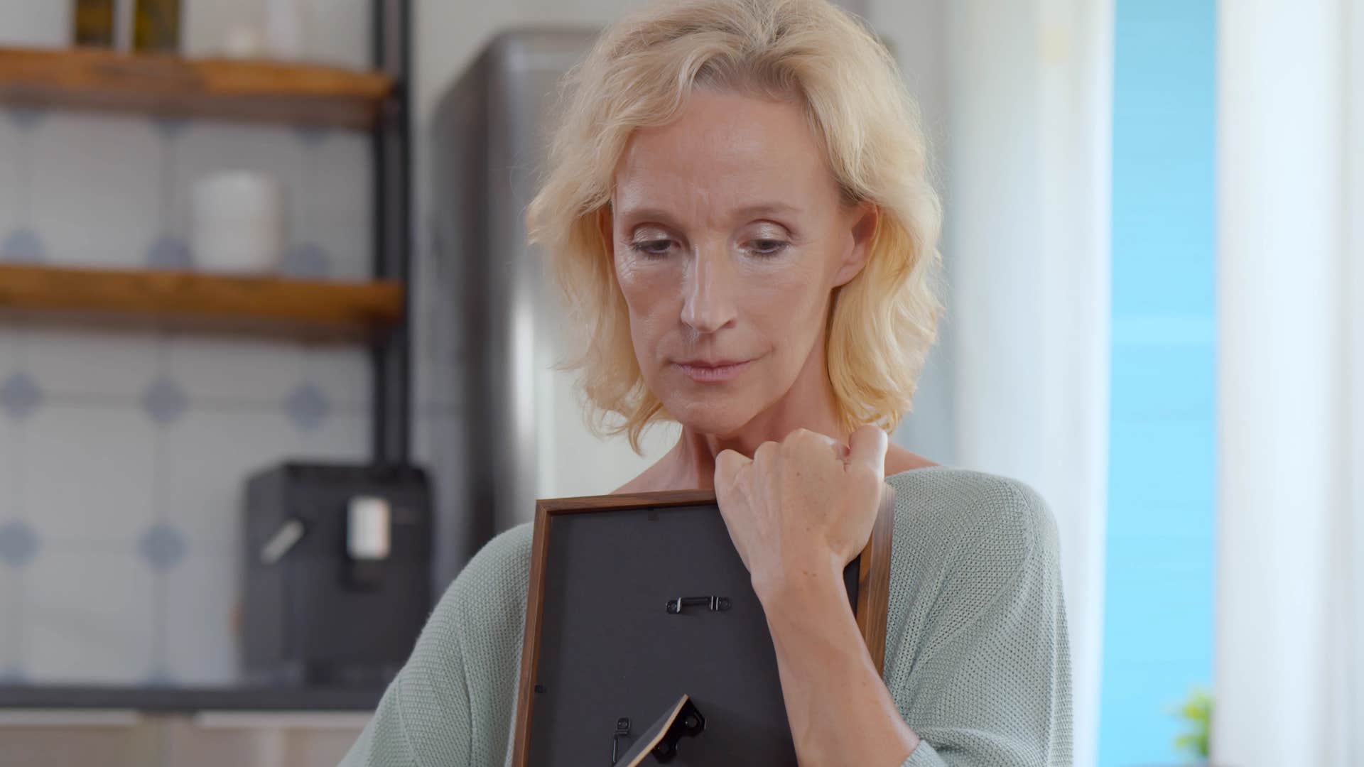 sad woman with too many reminders of the past holding a frame