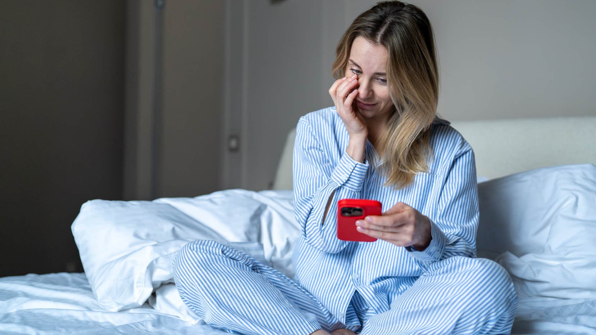 woman sitting in an unmade bed looking upset