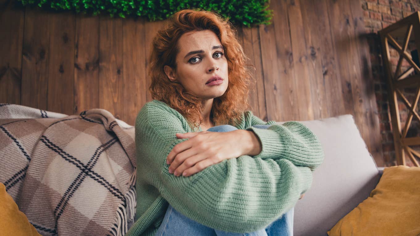 Things Feng Shui Experts Usually Find In The Homes Of People Who Are Struggling woman sitting on her couch struggling emotionally