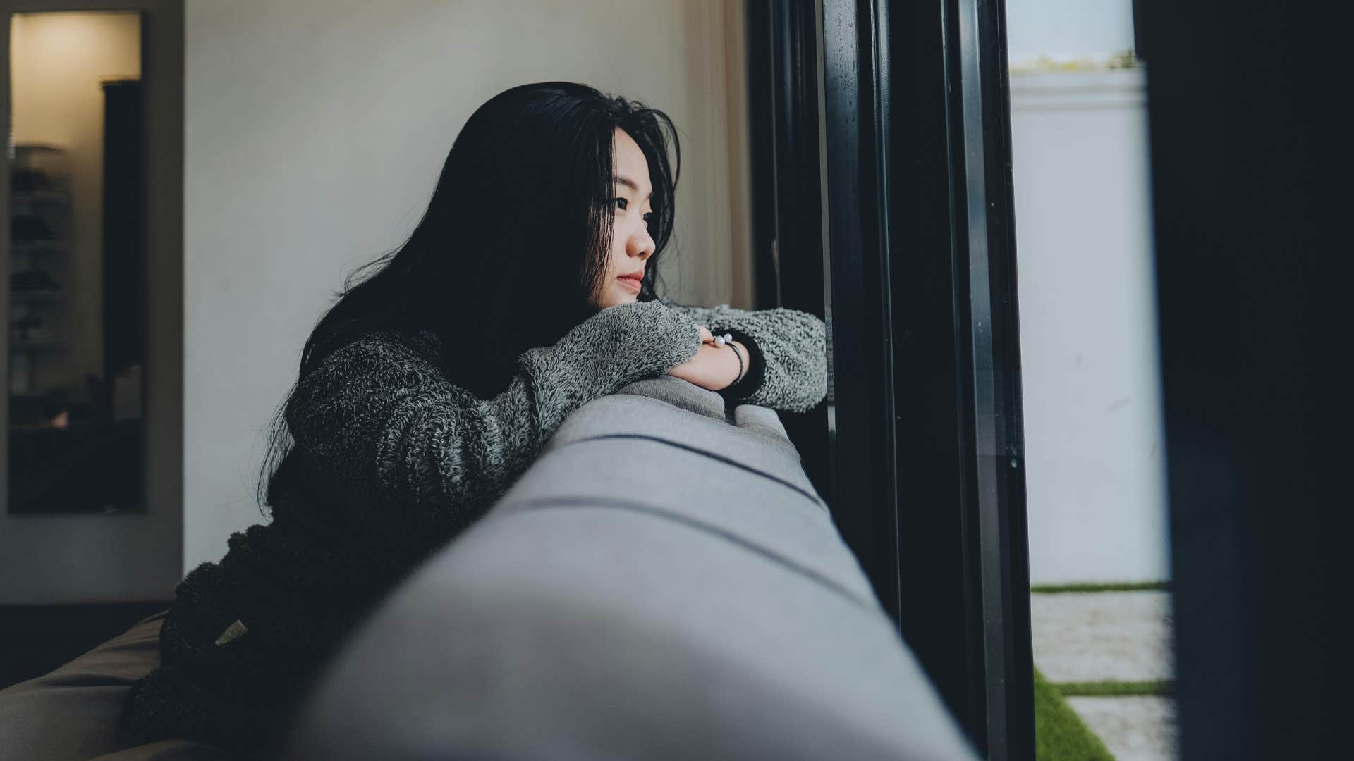 woman in gray shirt not confident as she stares out the window