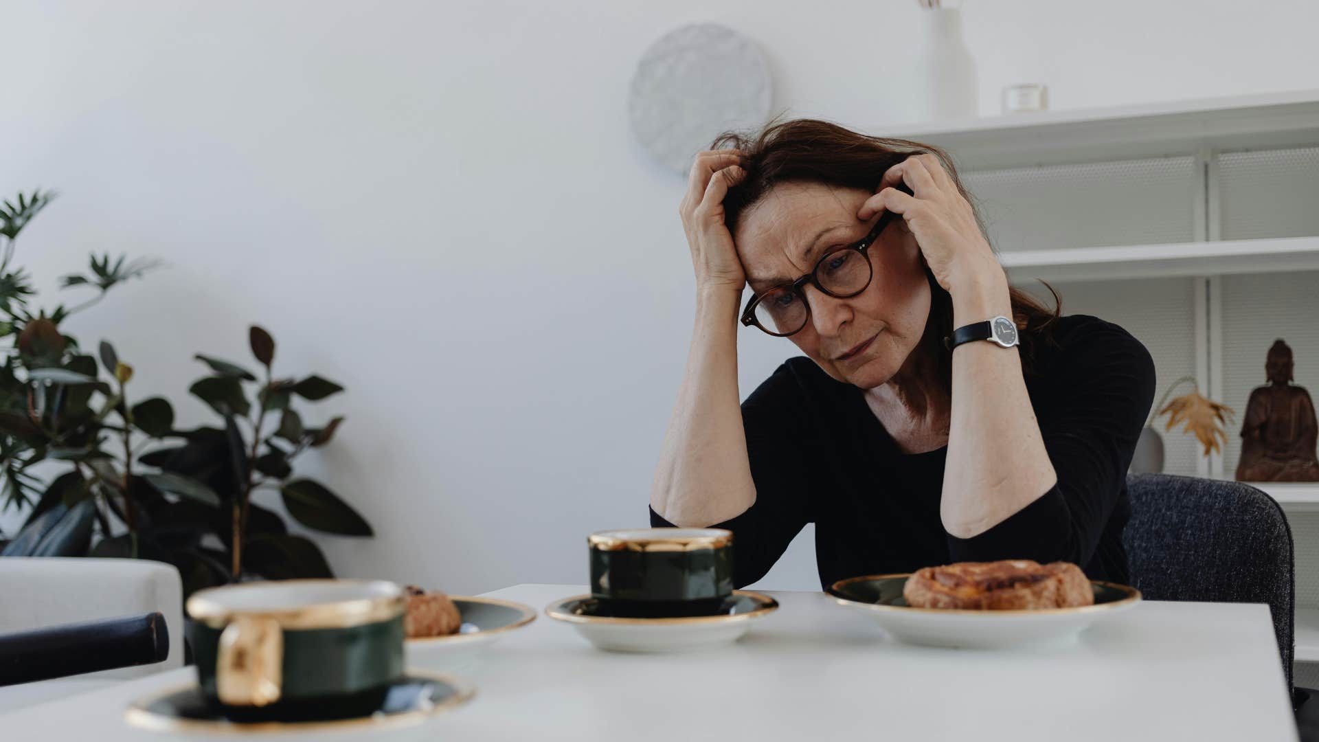 woman in black neglects her own growth as she sits at table not hungry