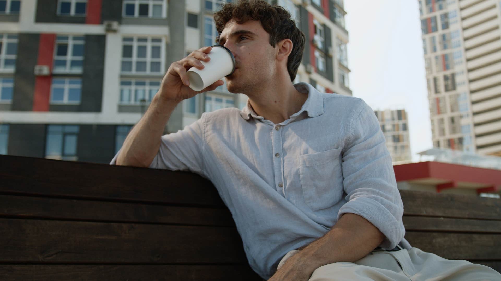 millennial man drinking coffee romanticizing the little things outside