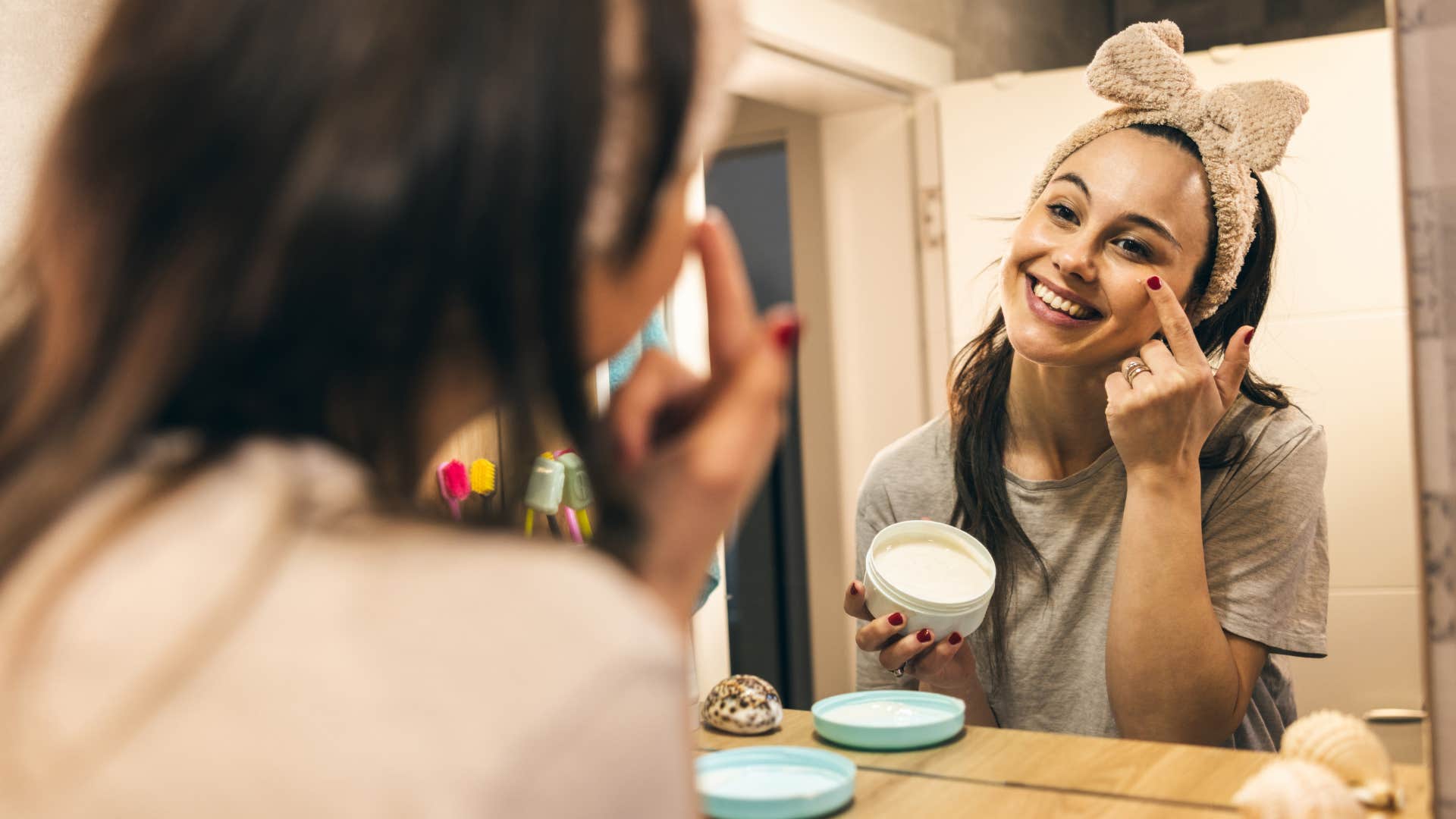 millennial woman doing her skincare routine in a mirror