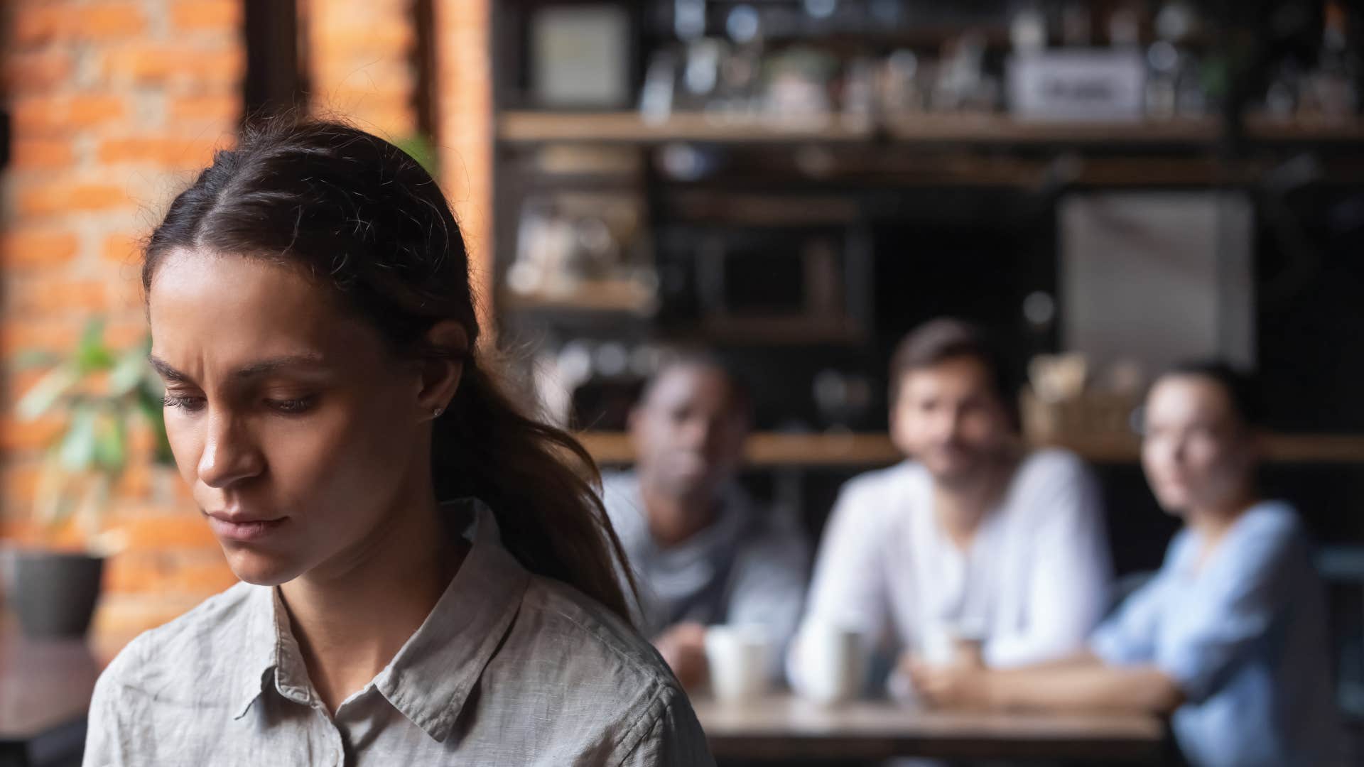 woman in gray shirt looking upset as she tolerates disrespect
