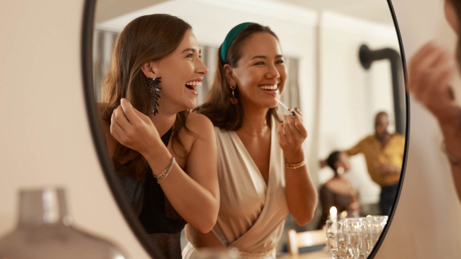 two women laughing together while looking in mirror