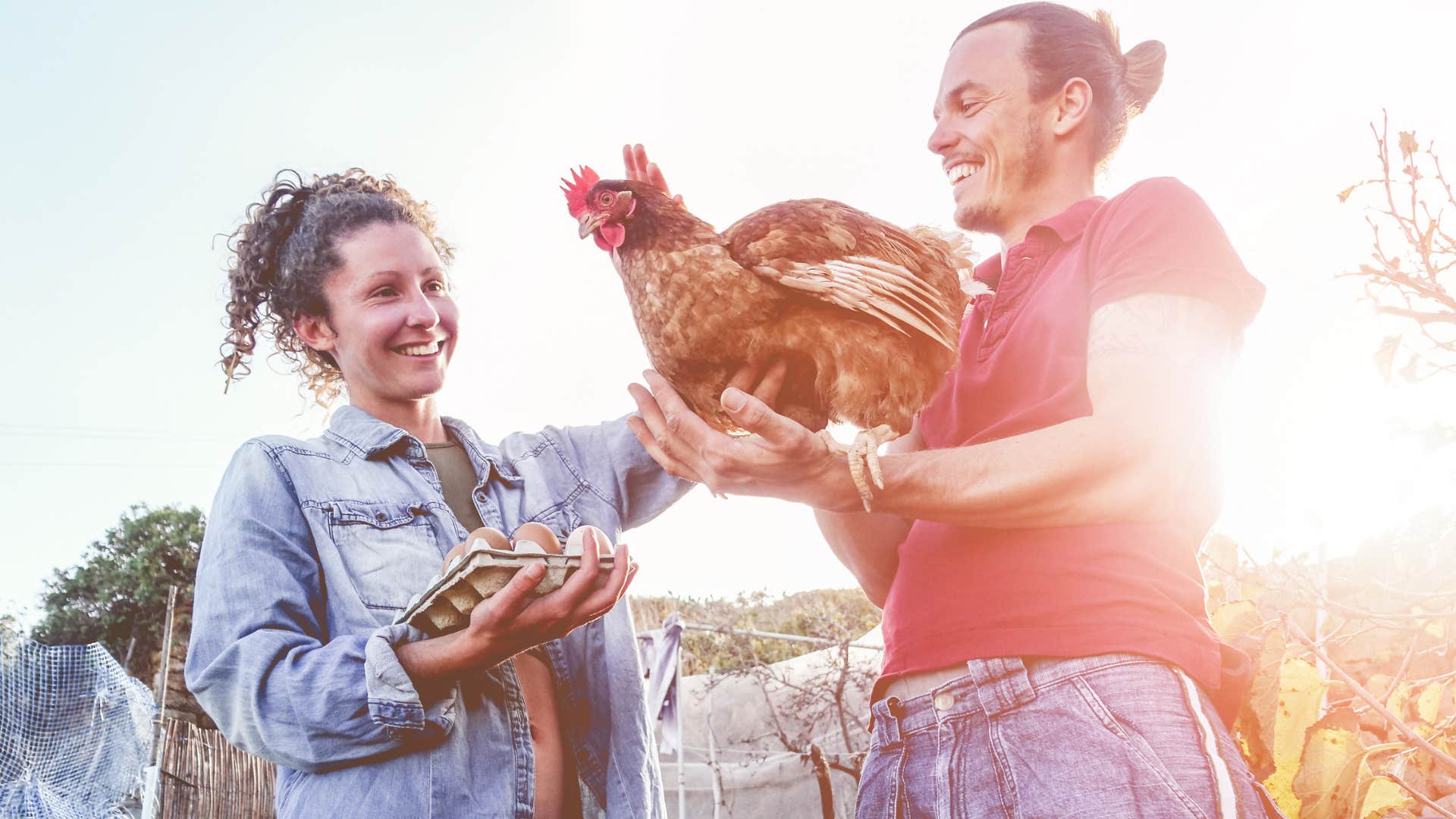 Couple with chickens in the backyard smiling.