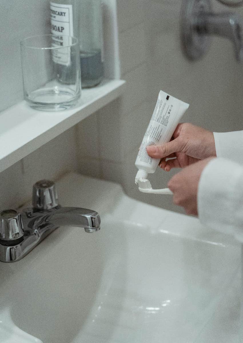 person putting toothpaste on a toothbrush
