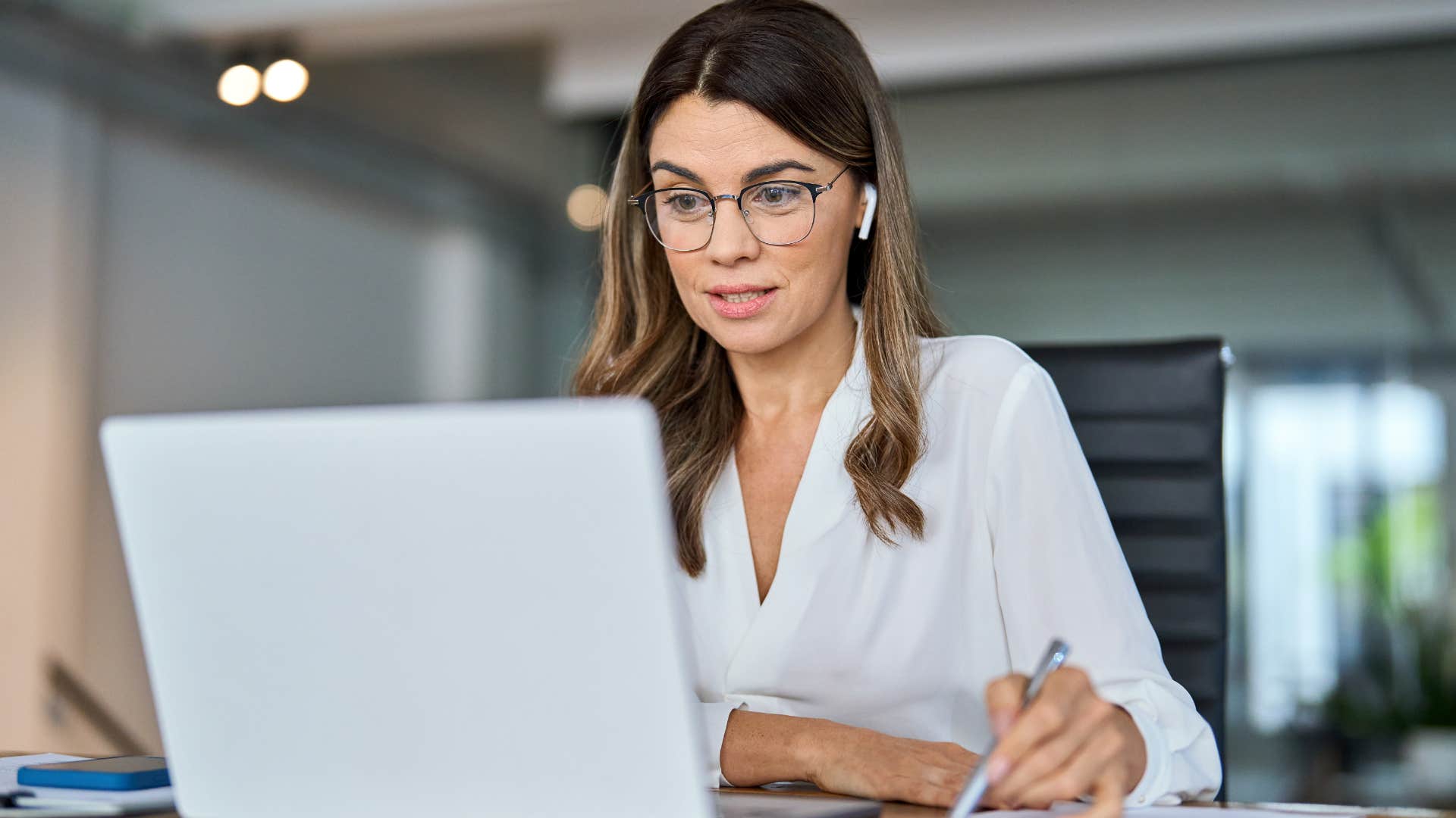 An assistant smiling and working on her laptop.