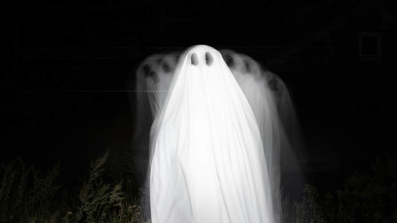 Travelers Swear These Spooky Places Have The Weirdest, Most Unexplainable Energy Person dressed as a ghost in a forest, illustrating spooky places with unexplainable, mysterious energy that travelers report