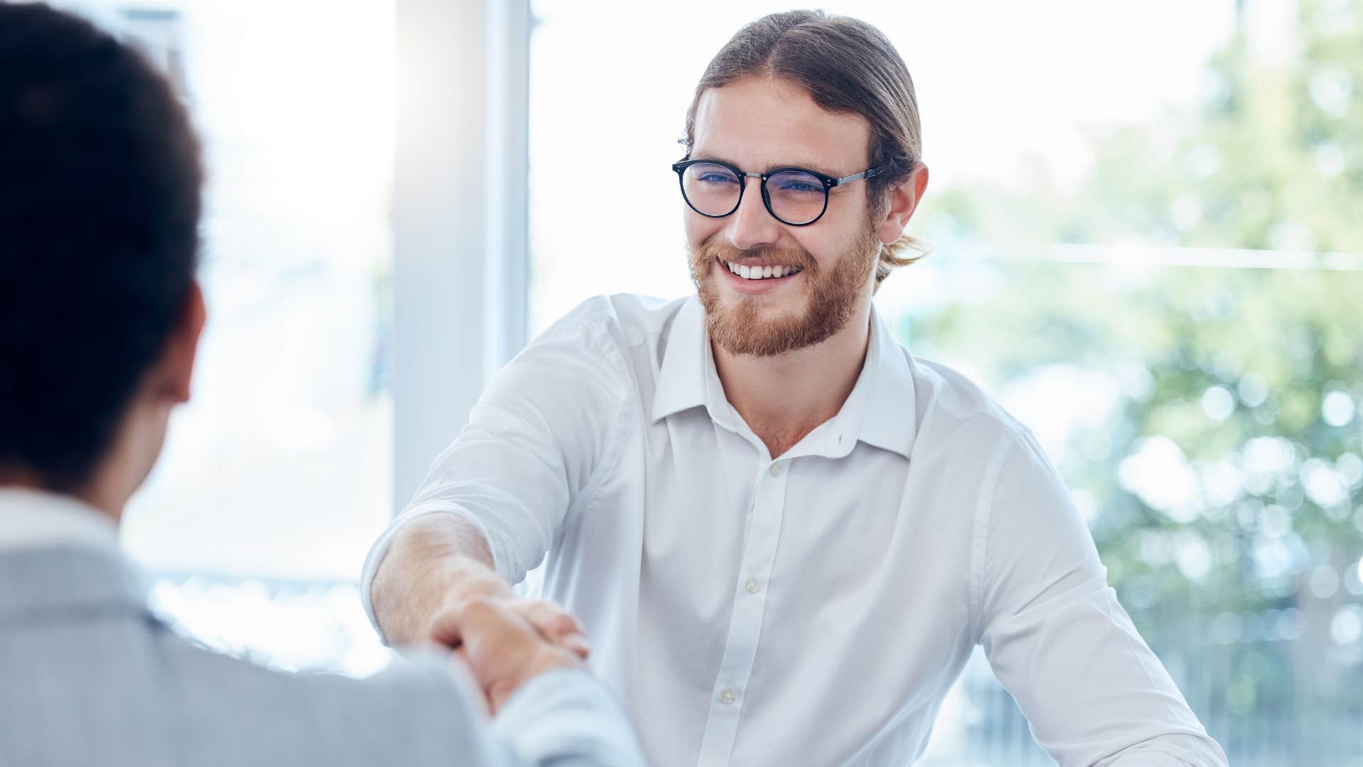 Self-assured man shaking hands with a friend.