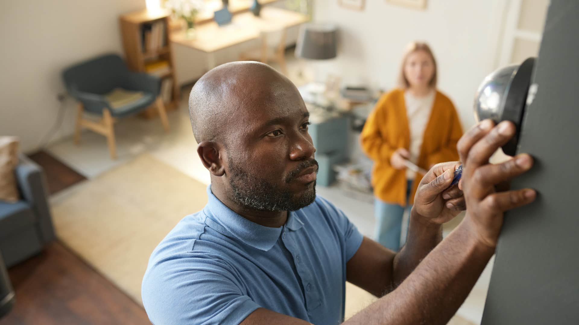gen x man fixing thermostat at home