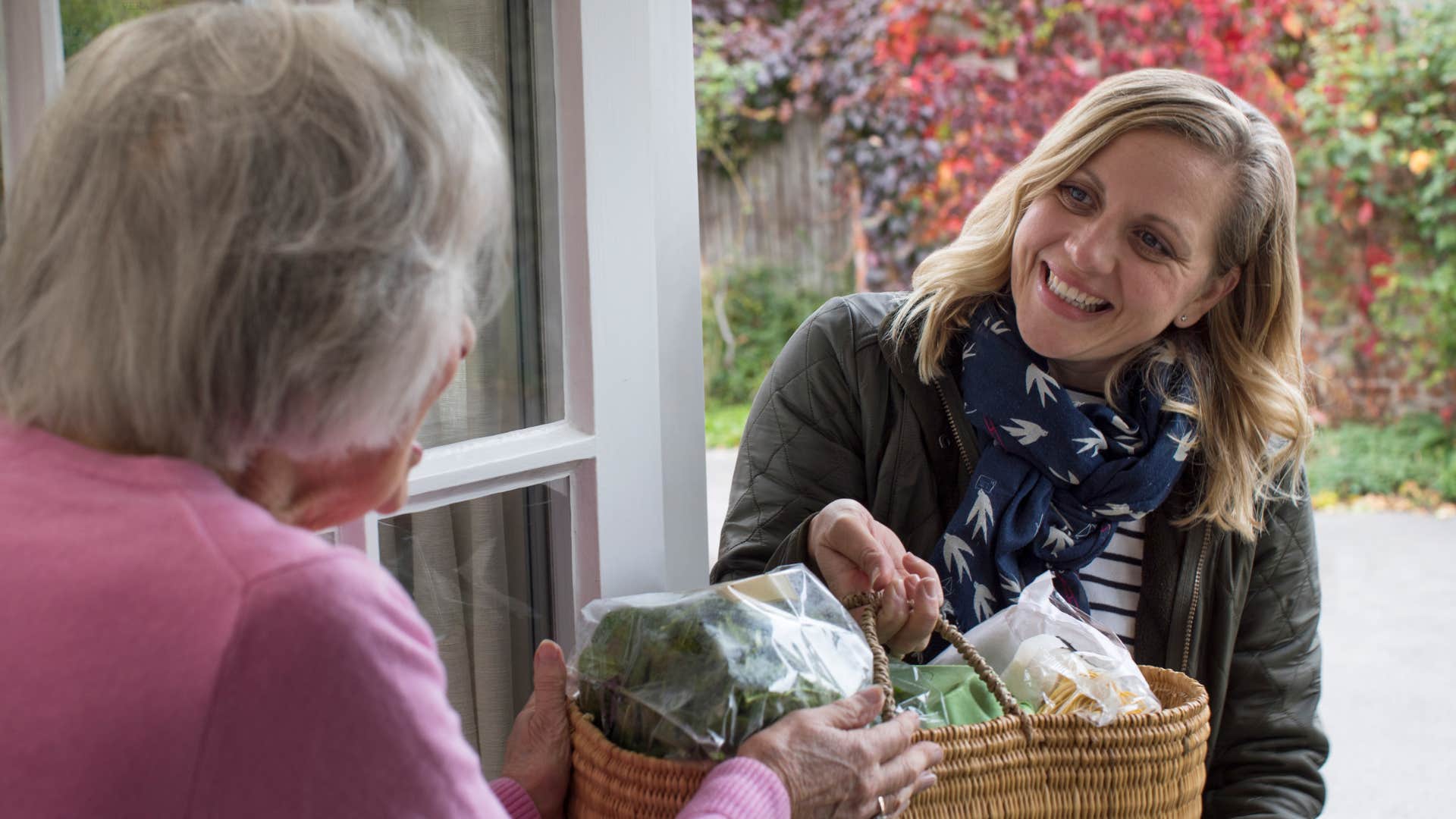 gen x woman dropping off food to elderly woman