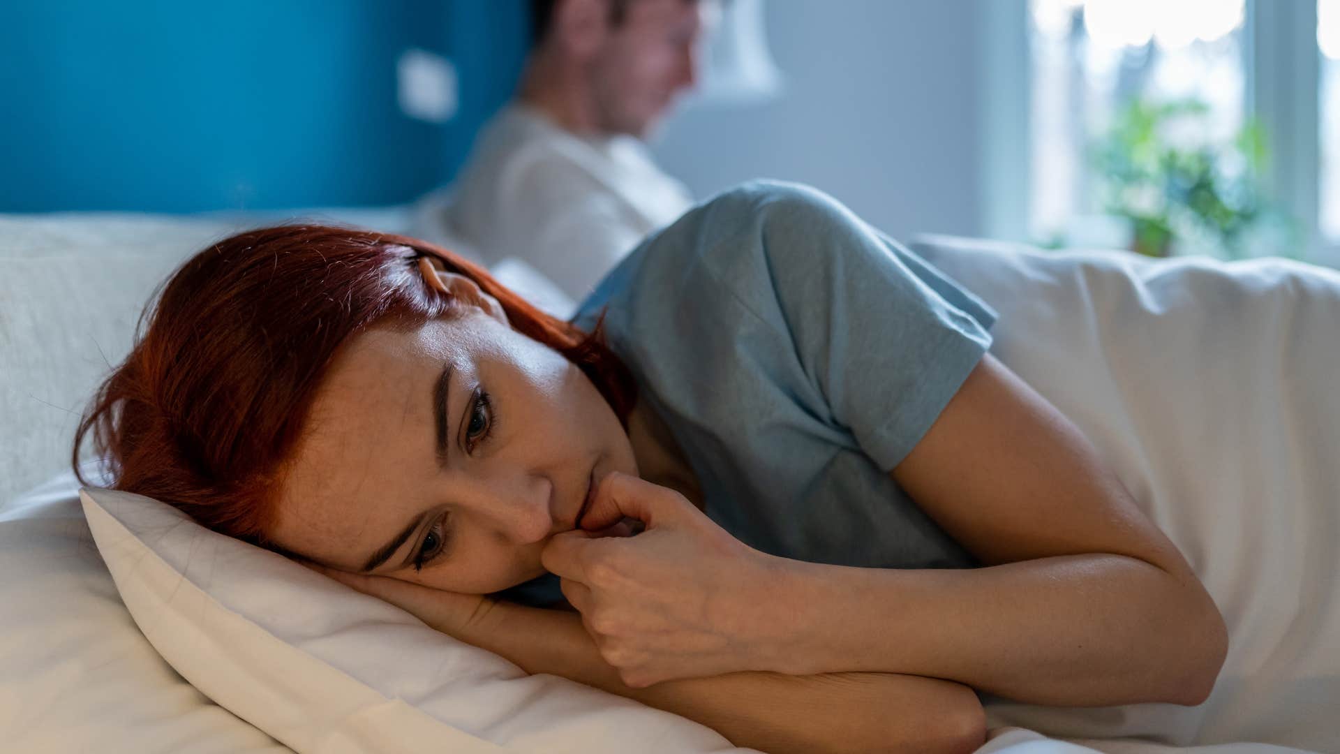 woman laying in bed with avoidant body language