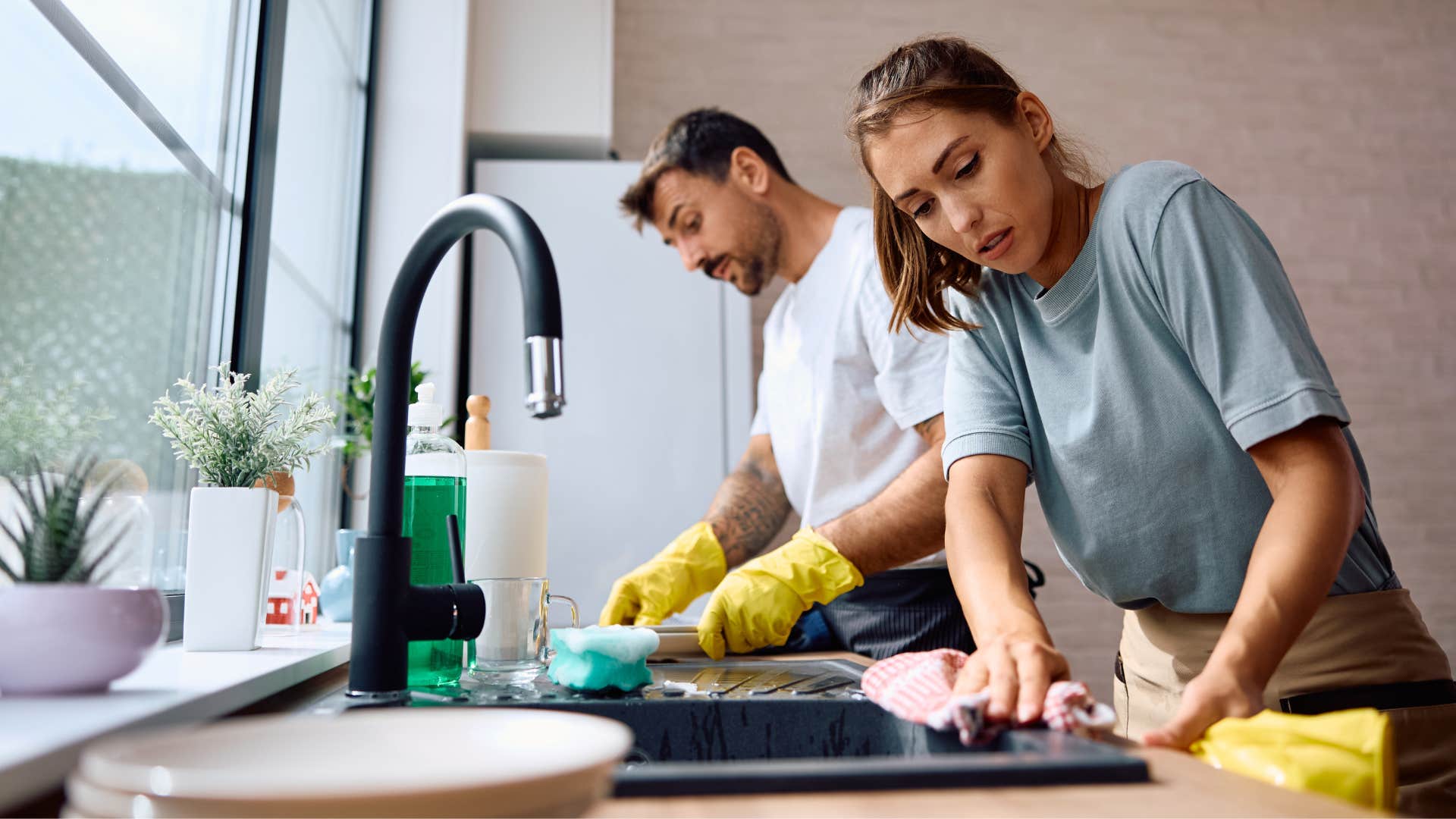 a wife who is so tired of doing everything for her husband usually say these things all the time it'd be faster if i just did it myself couple washing dishes annoyed woman saying it'd be faster if i just did it myself