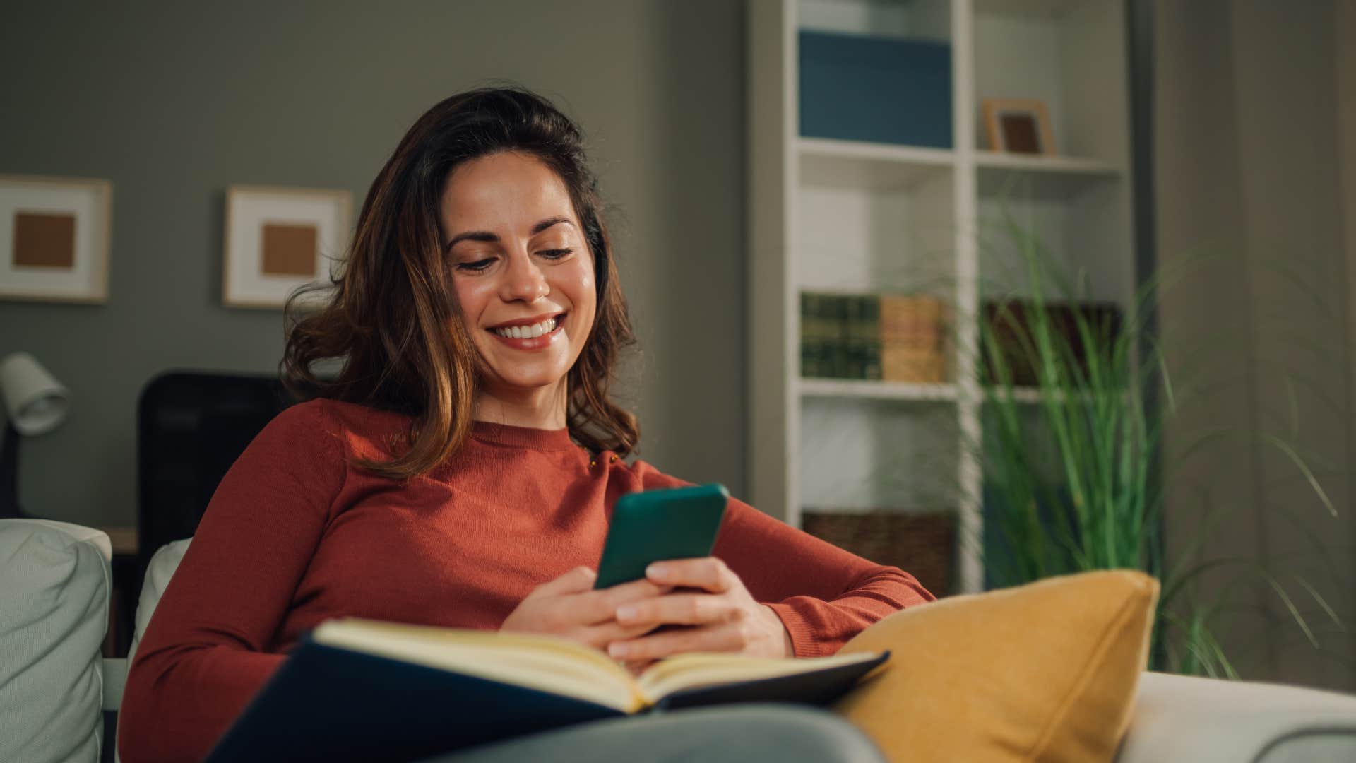 woman in red sweater smiling at her phone as she texts stop making me smile 