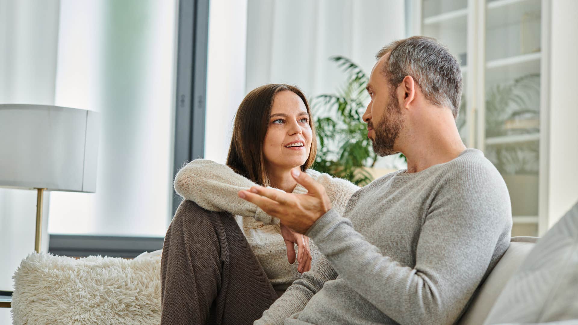 woman in gray shirt looking up at man and asking what kind of women do you like as man responds