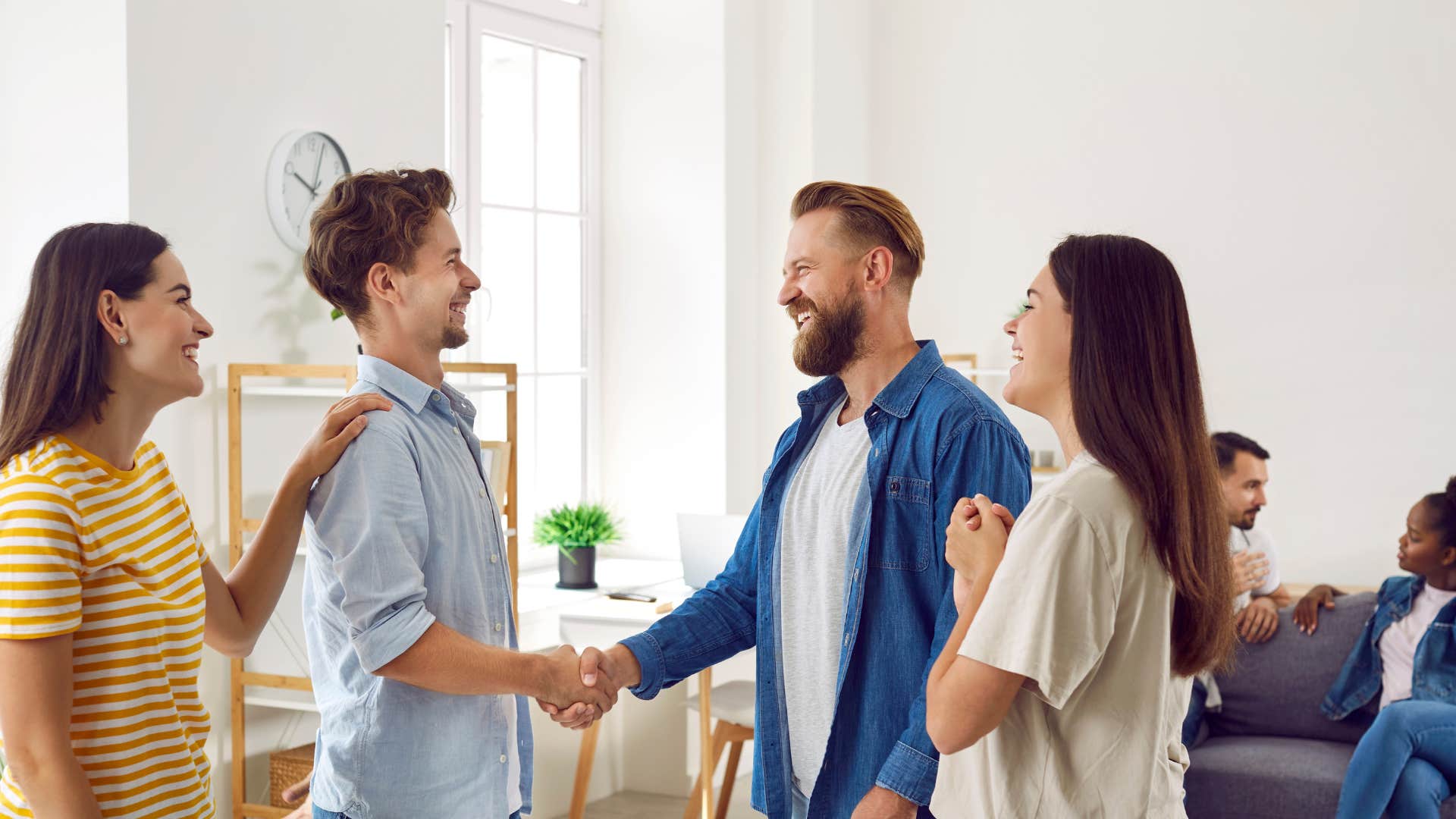 woman introducing man to her friends as man shakes hands