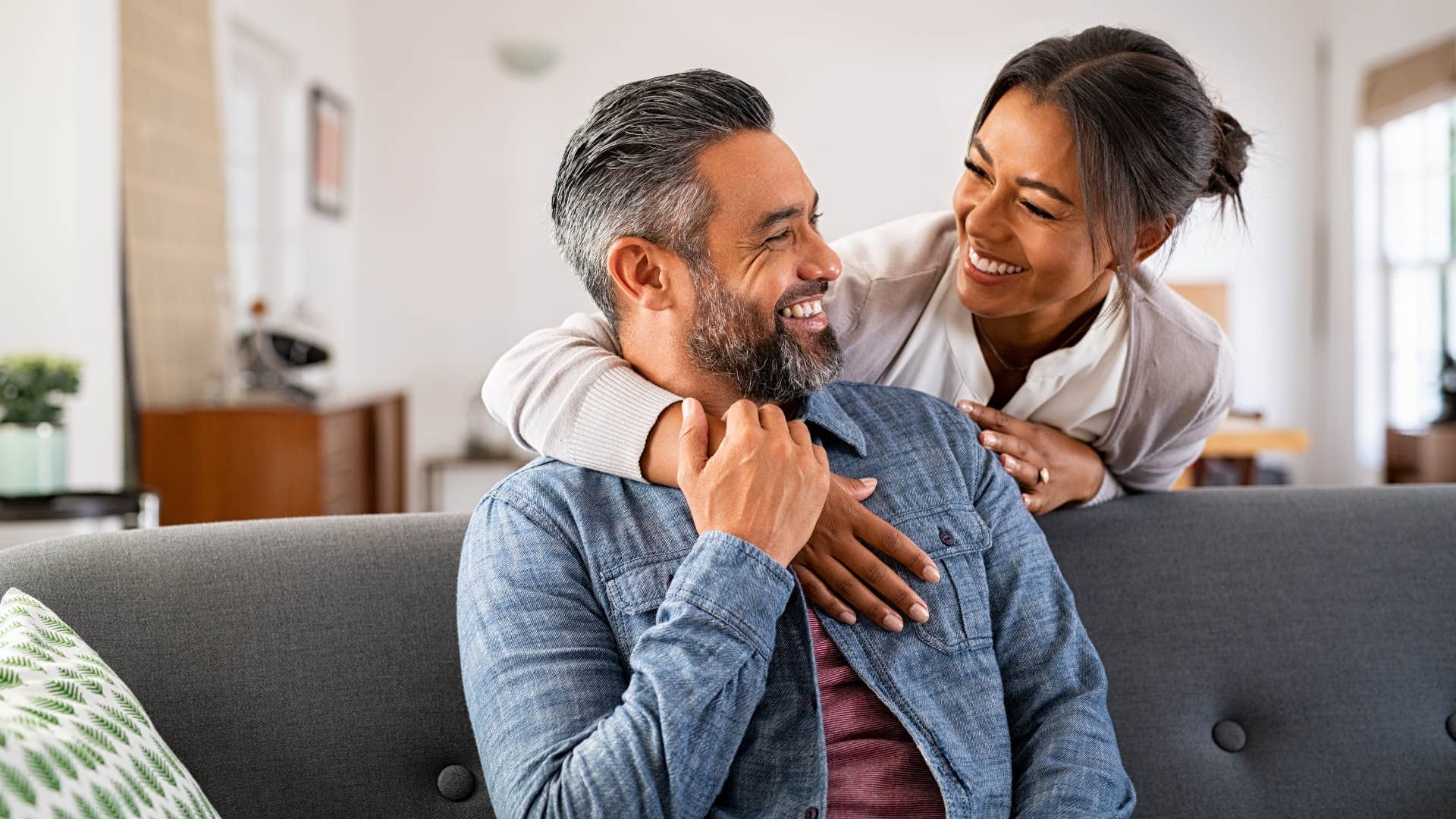 woman mirrors his energy as she smiles and hugs man from behind
