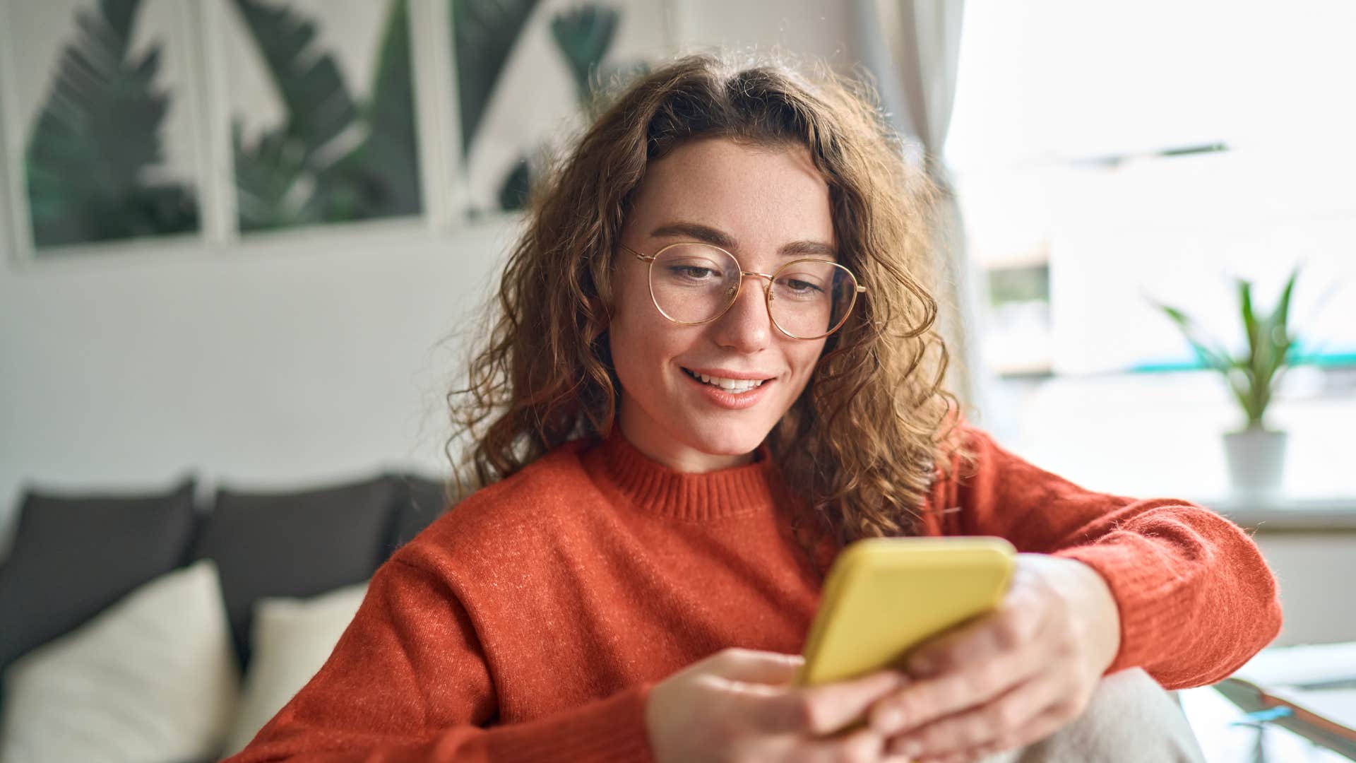 woman in red sweater responds to text messages instantly as she smiles