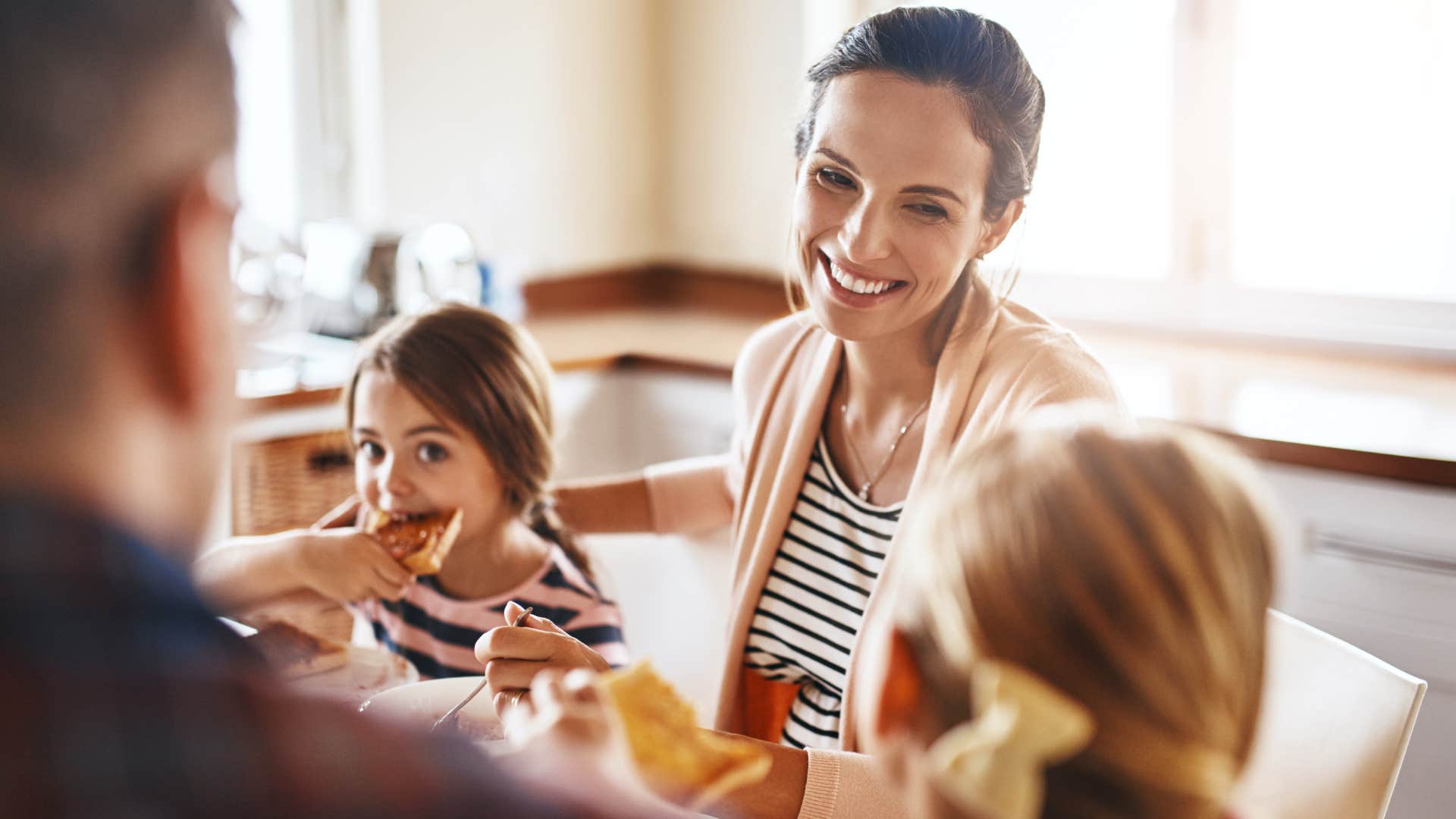 woman telling stories during a meal smiling at her kids