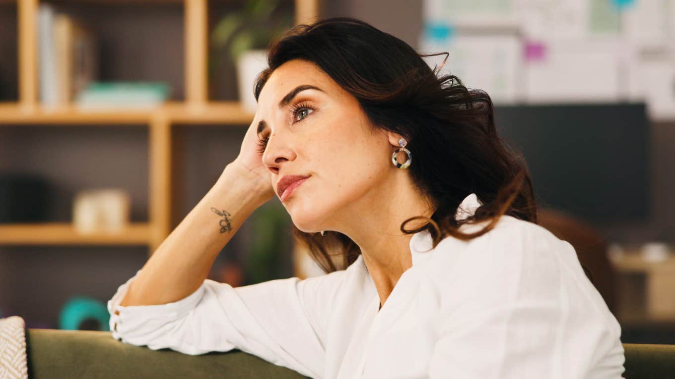 Lonely woman sitting on sofa in quiet home, deep in anxious reflection, wondering if she married the right person — emotional insight into midlife relationship doubt.