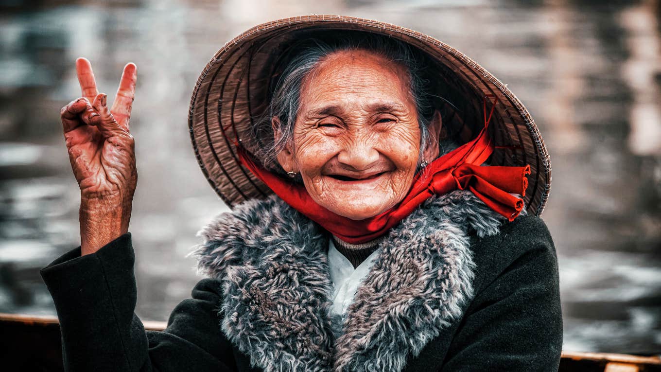 Elderly woman in a hat smiling showing the art of aging calmly and habits of people who age with grace, not panic.