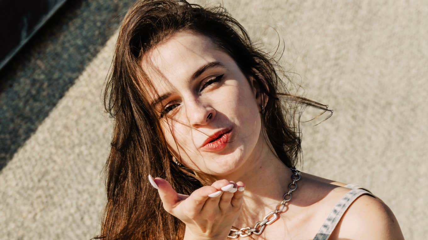 Flirty woman blowing a kiss, illustrating subtle body language tricks that naturally drive attraction and chemistry