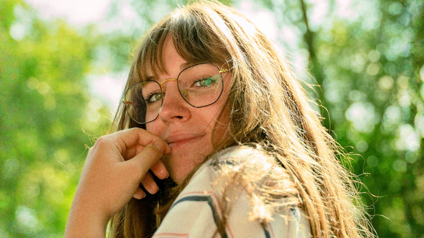 Woman looking over her shoulder with a subtle flirty smile, capturing the scientific signs of real human chemistry and falling in love.