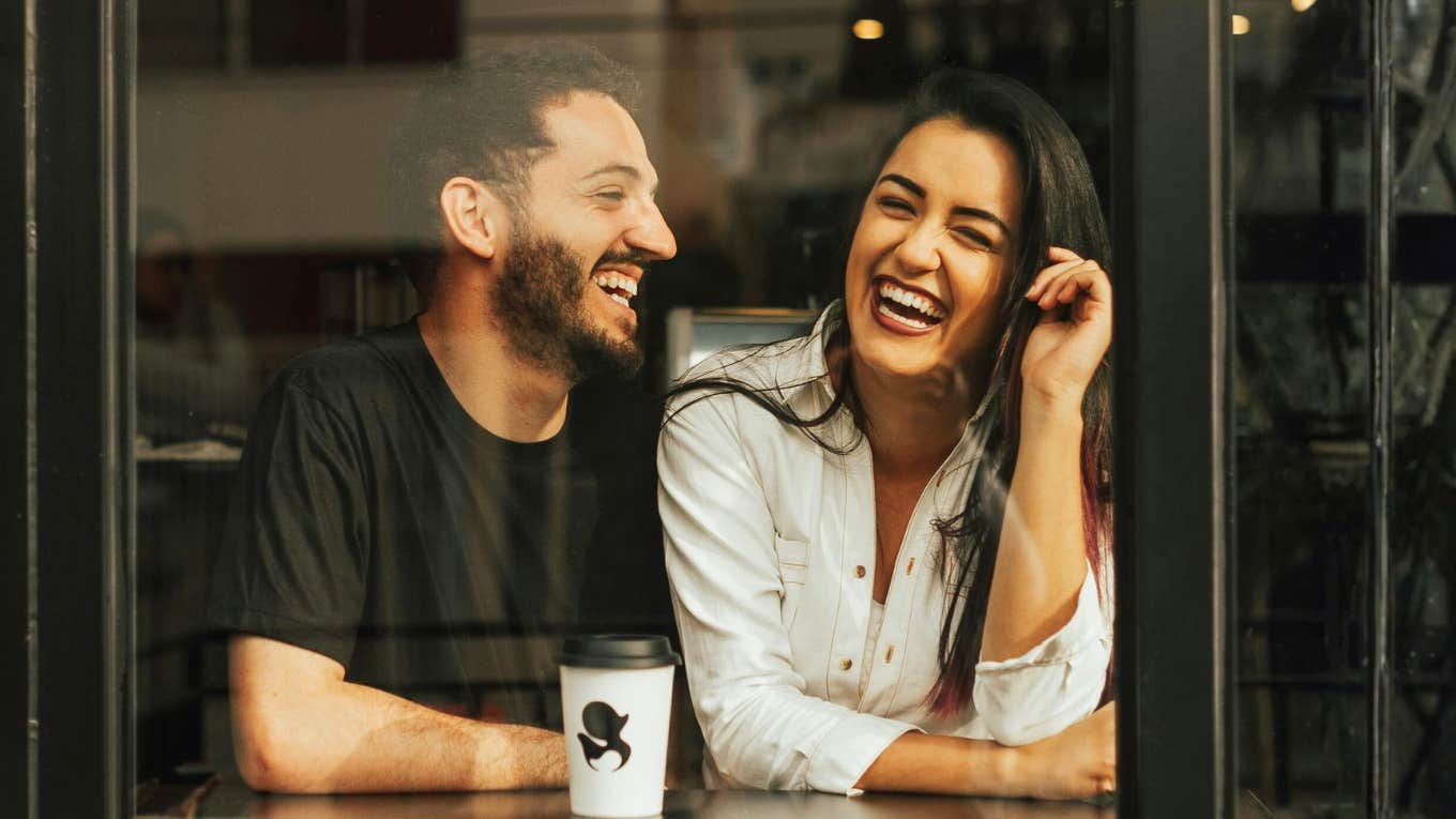 Attentive man listening as a woman opens up laughing showing the art of making conversation and questions that help her share more