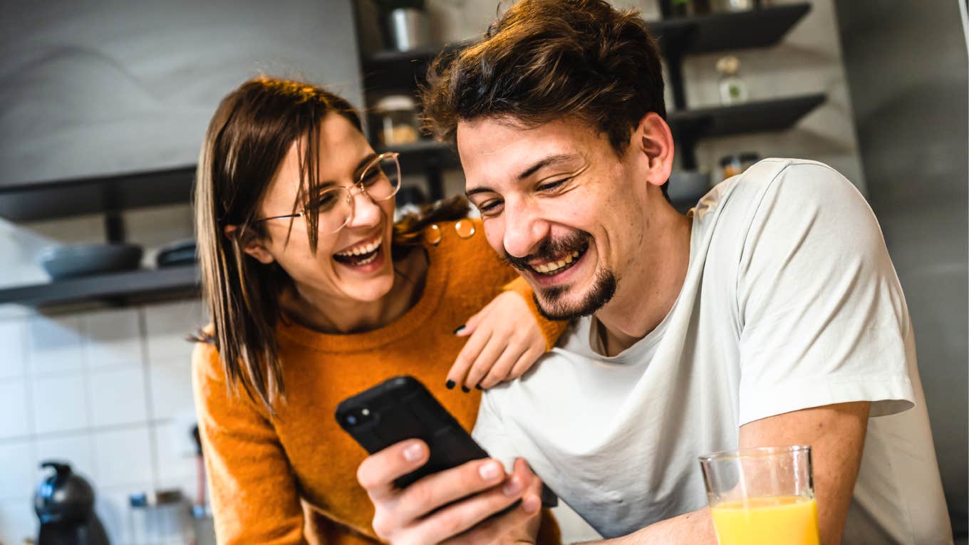 Happy couple laughing together in kitchen, showing the positive outcomes of relationship repair and how couples counseling can restore connection and joy.
