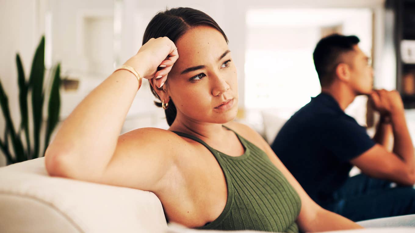 Couple sitting silently on couch, emotional distance and tension showing clear signs it’s time for couples counseling and relationship repair.