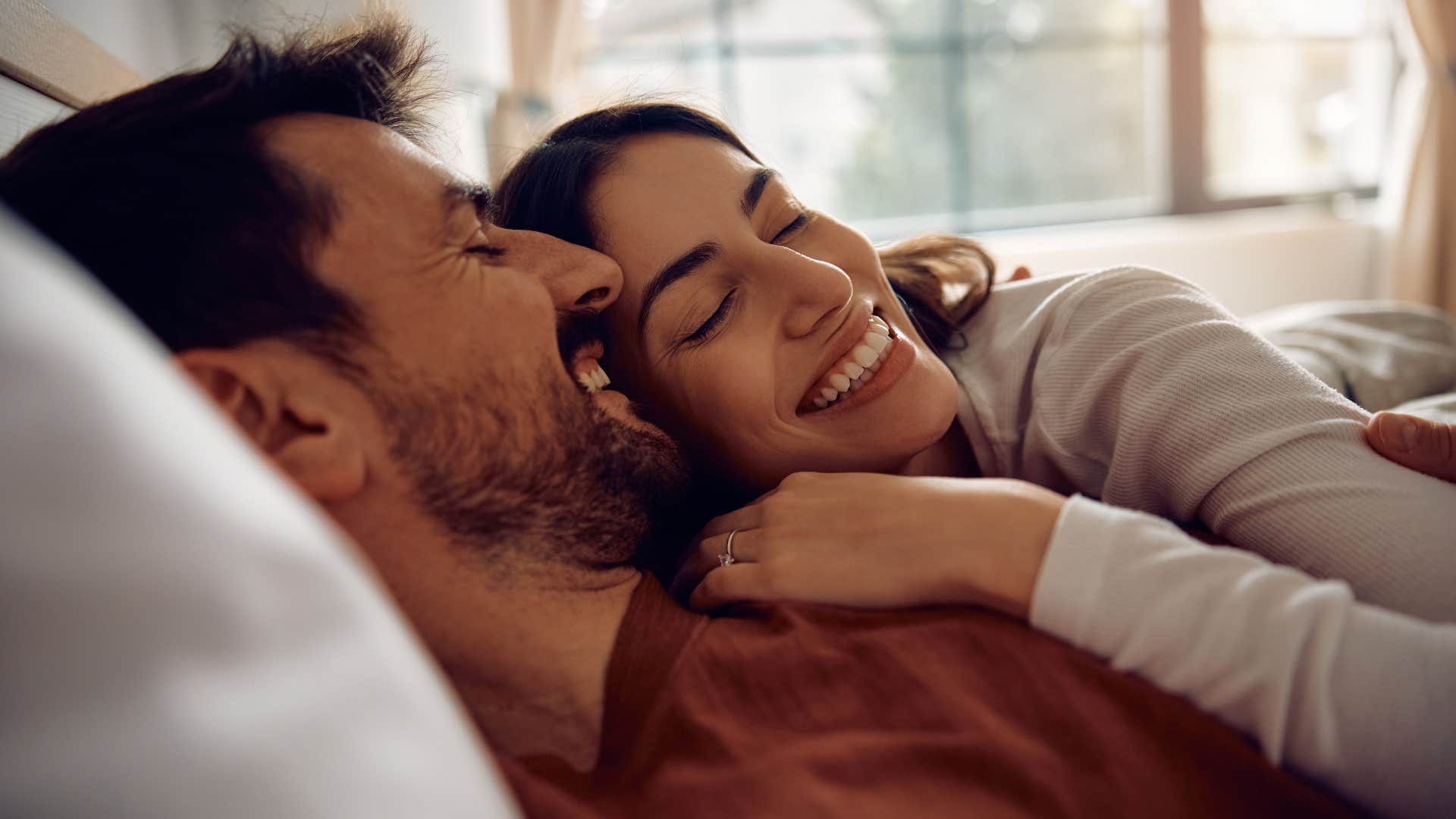happy couple feeling perfectly fine cuddling in bed