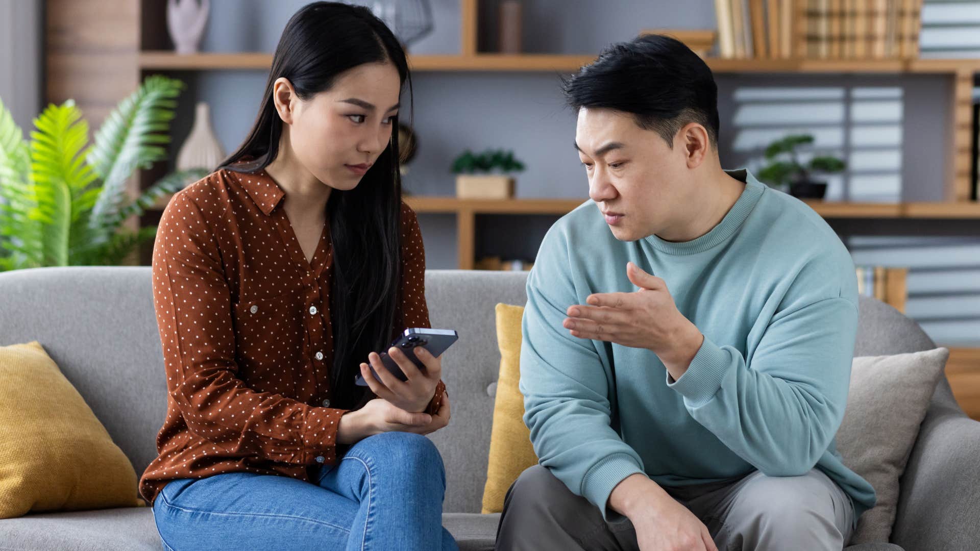 woman on her phone while husband tries to talk to her