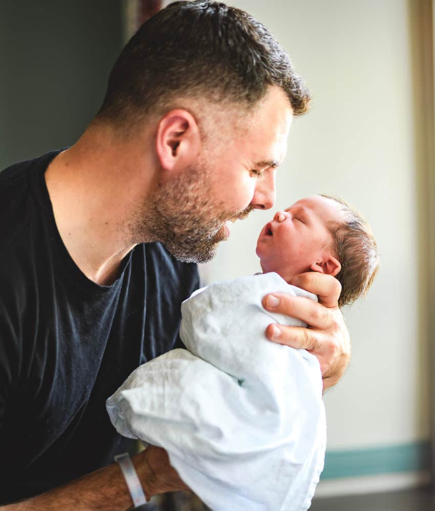Dad with newborn happy even though the cost of childbirth financially devastating